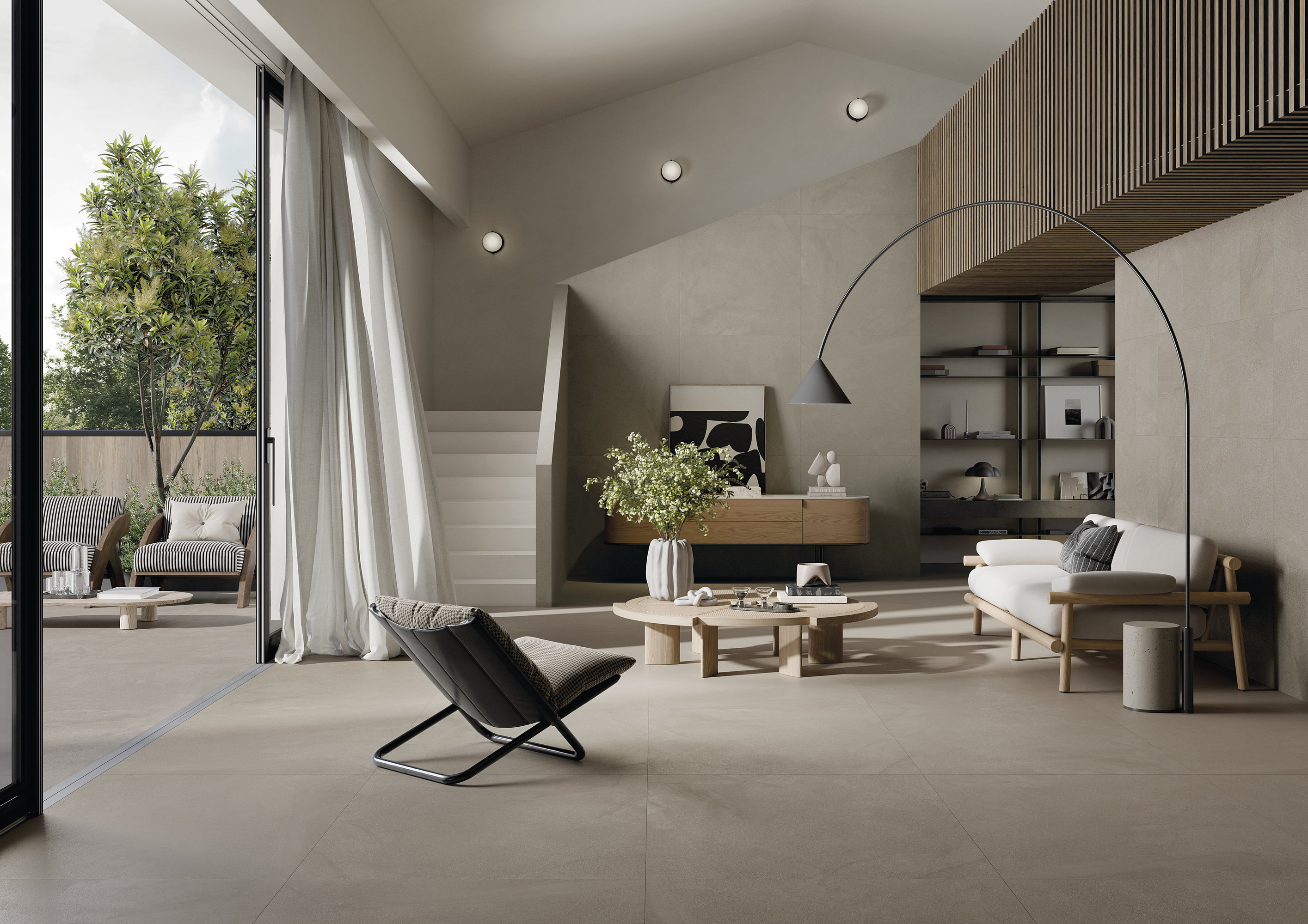 Des carreaux clairs et grand format créent une transition fluide entre le salon moderne et la terrasse.