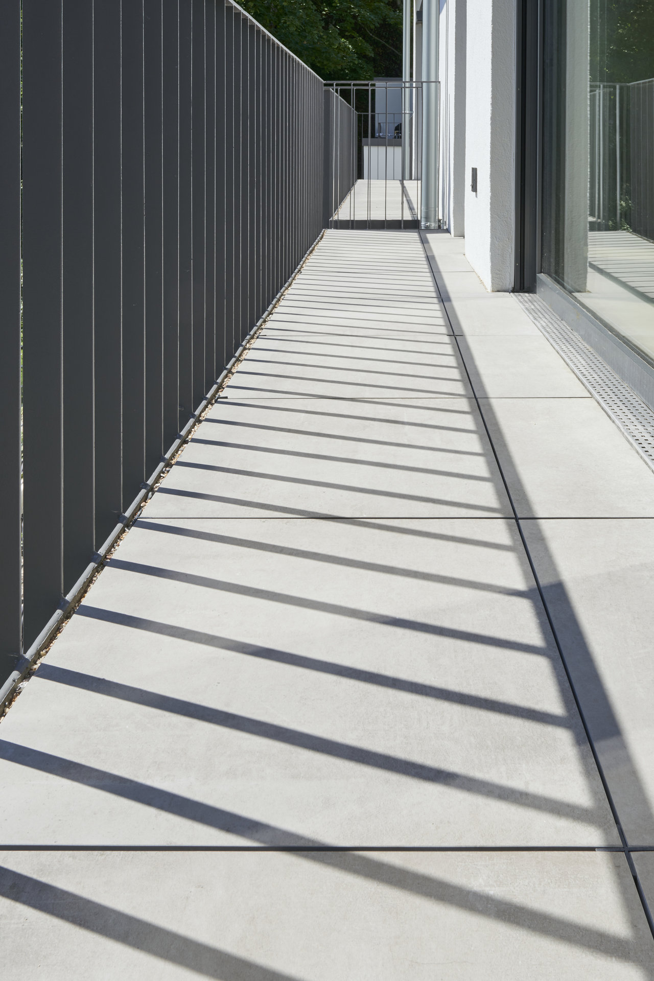 Carrelage extérieur clair sur un balcon moderne avec un jeu d'ombres élégant.