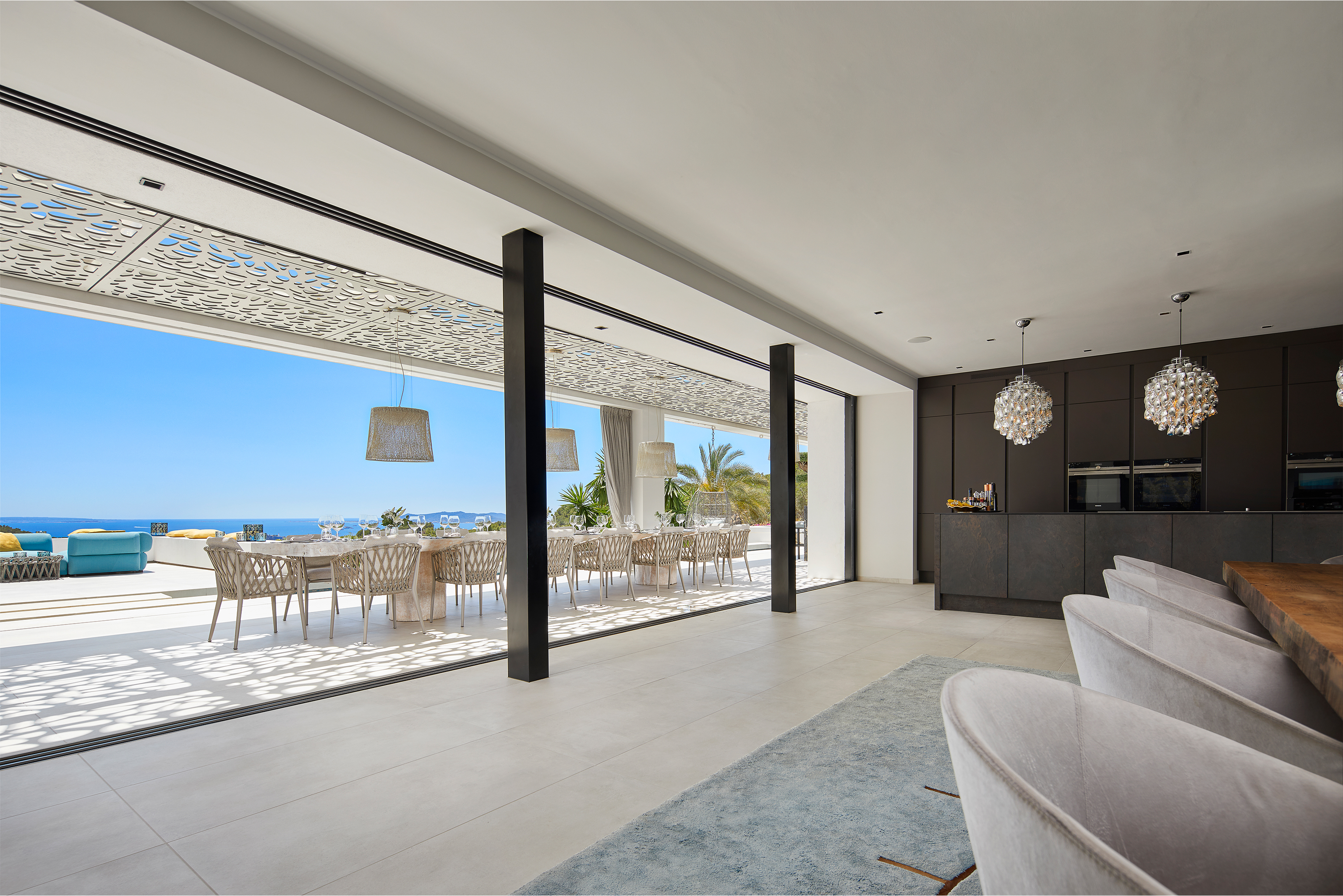 Salon luxueux avec carrelage Porcelaingres, s'ouvrant sur une terrasse vue mer.