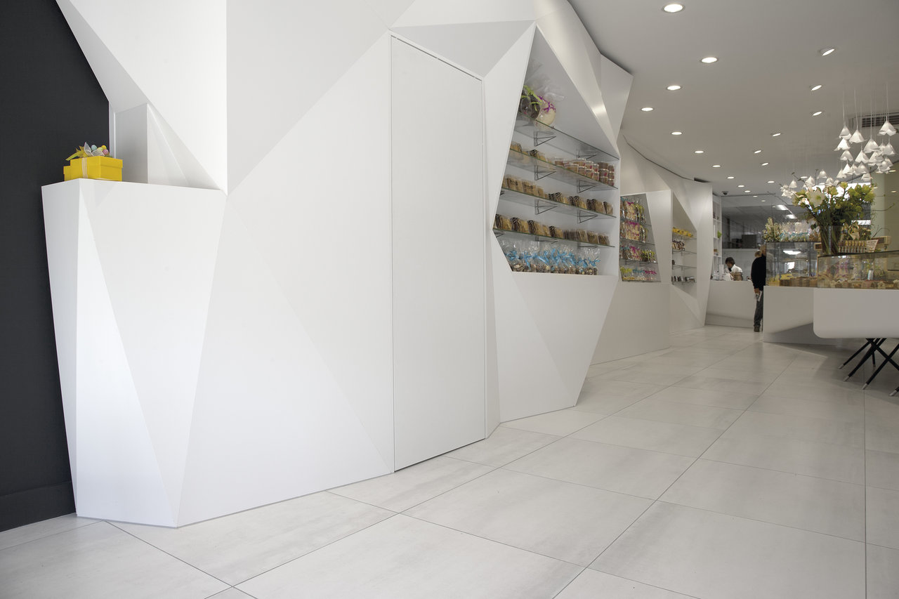 Carreaux de sol grand format, clairs, dans une ambiance de magasin moderne et minimaliste.