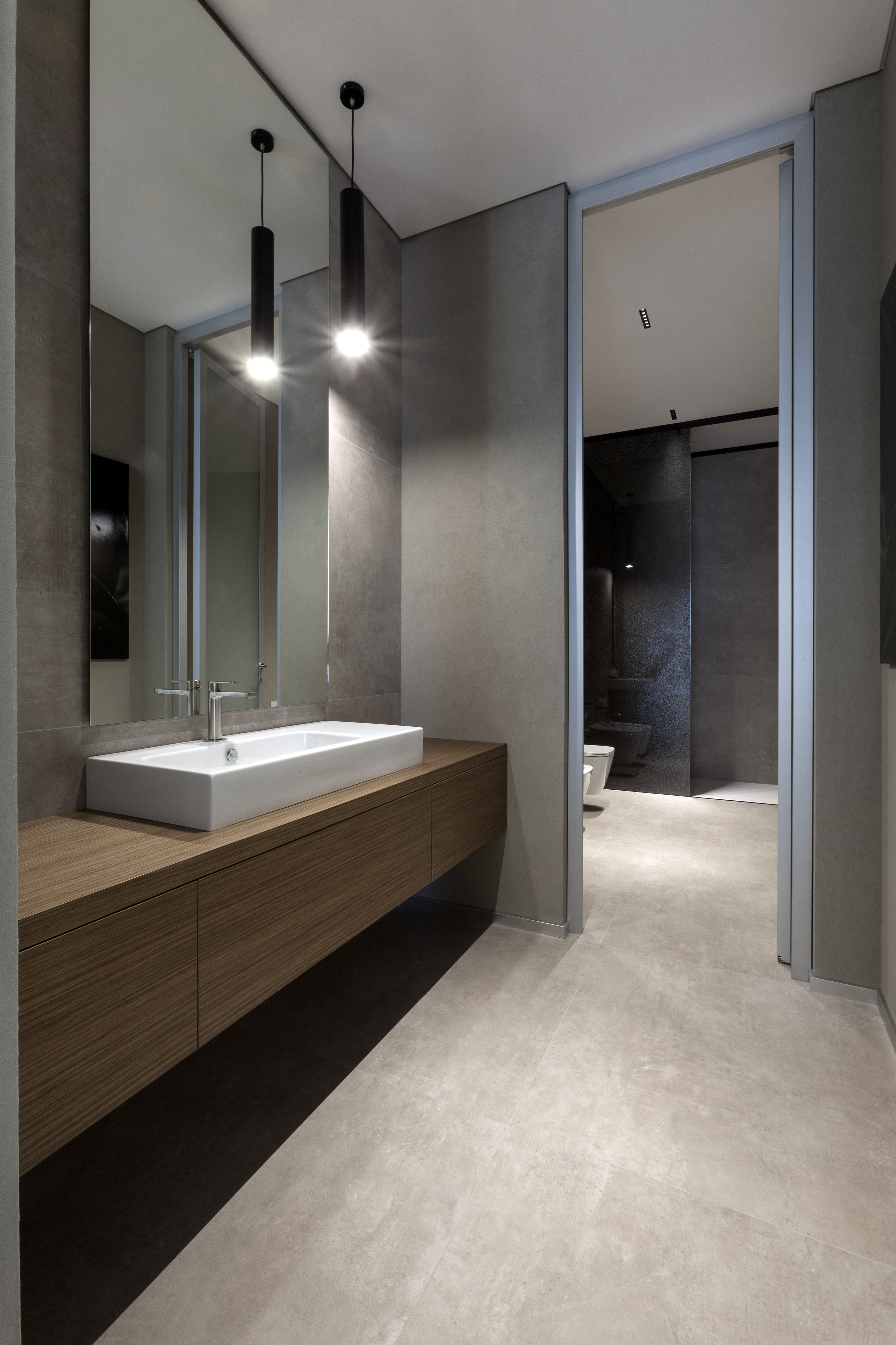 Élégante salle de bain avec grands carreaux effet béton et vasque bois suspendue.