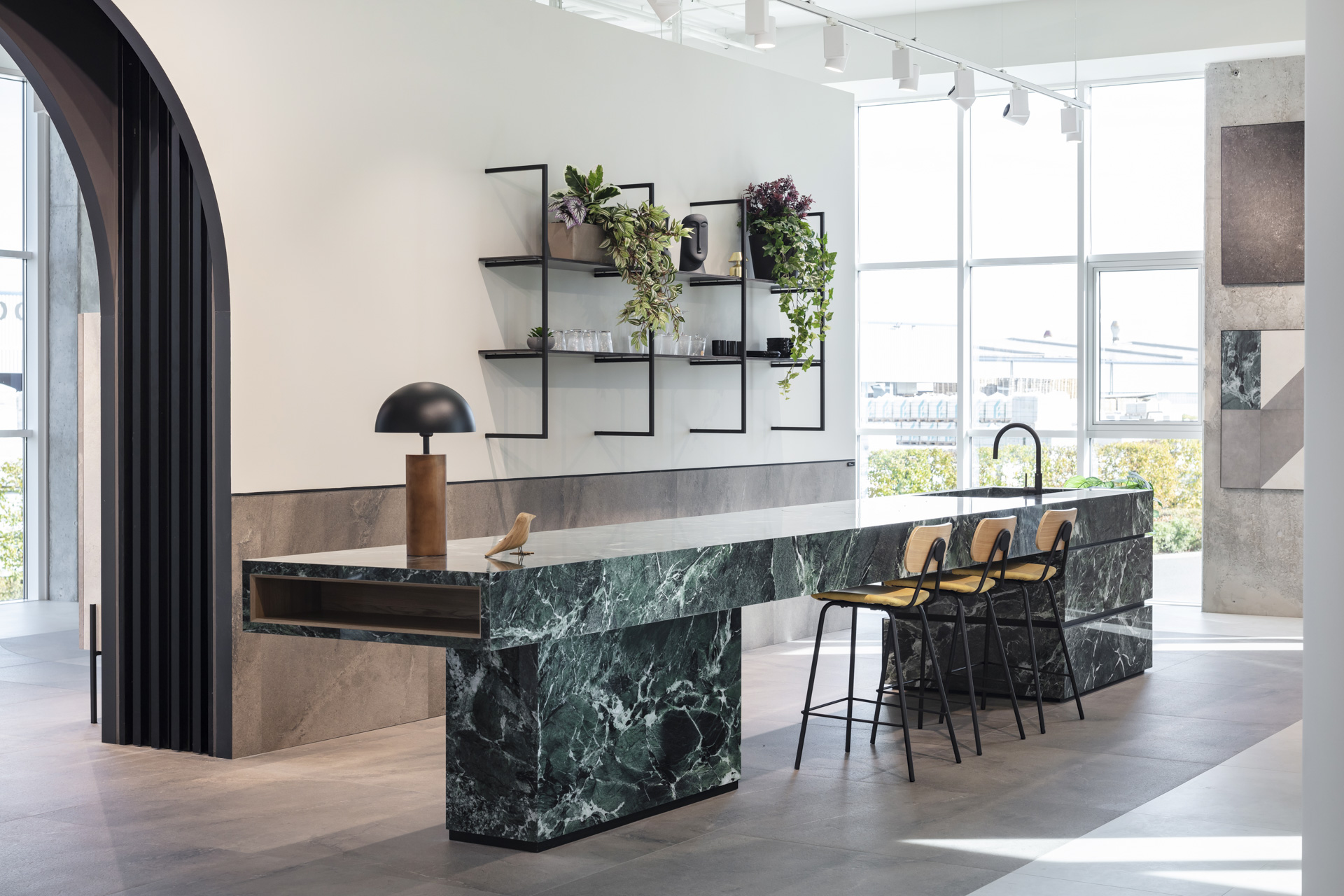 Îlot de cuisine moderne en carreaux effet marbre vert foncé et sol clair.