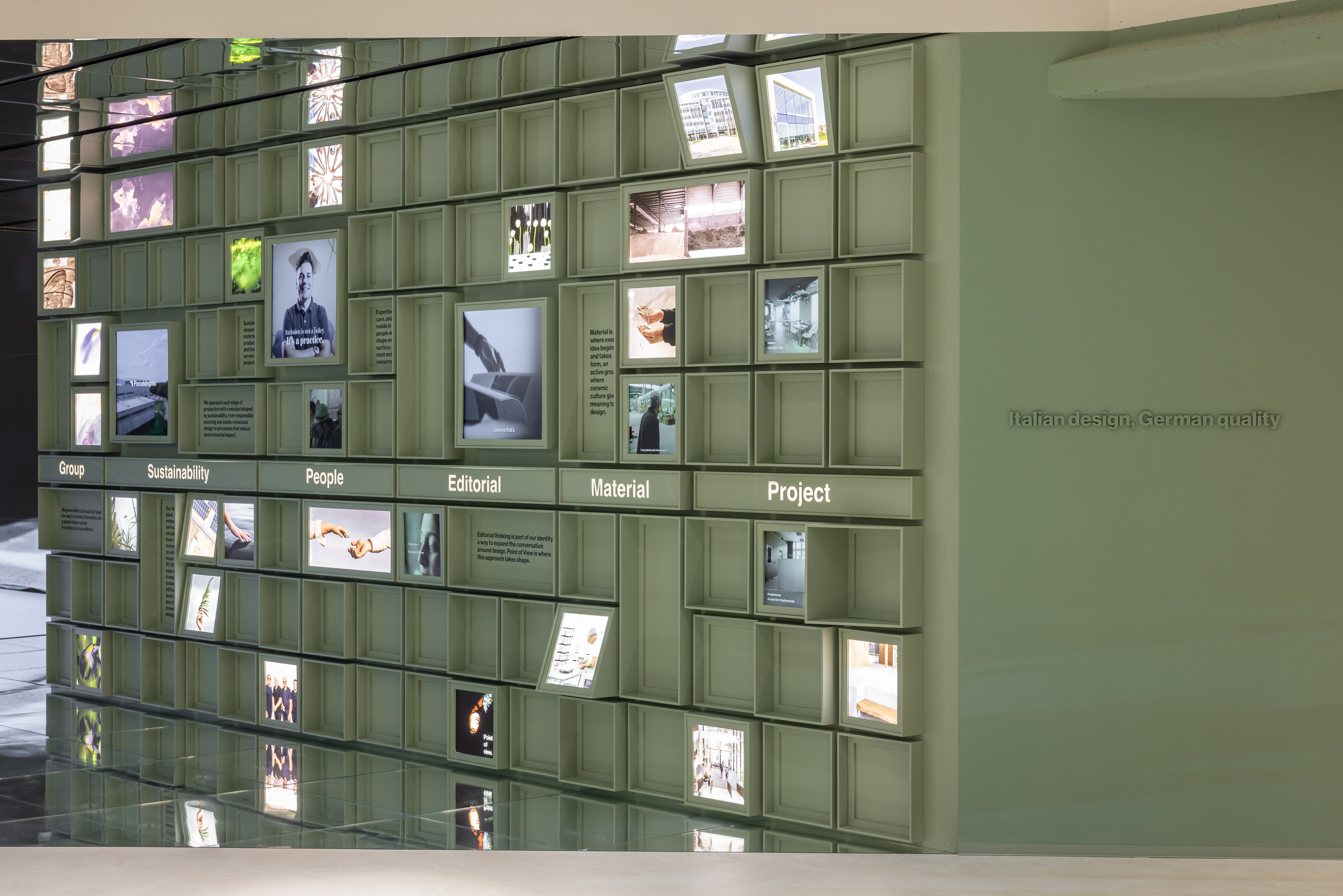 Beleuchtete Ausstellungswand einer Fliesenmarke mit Fokus auf Material und Projekte.
