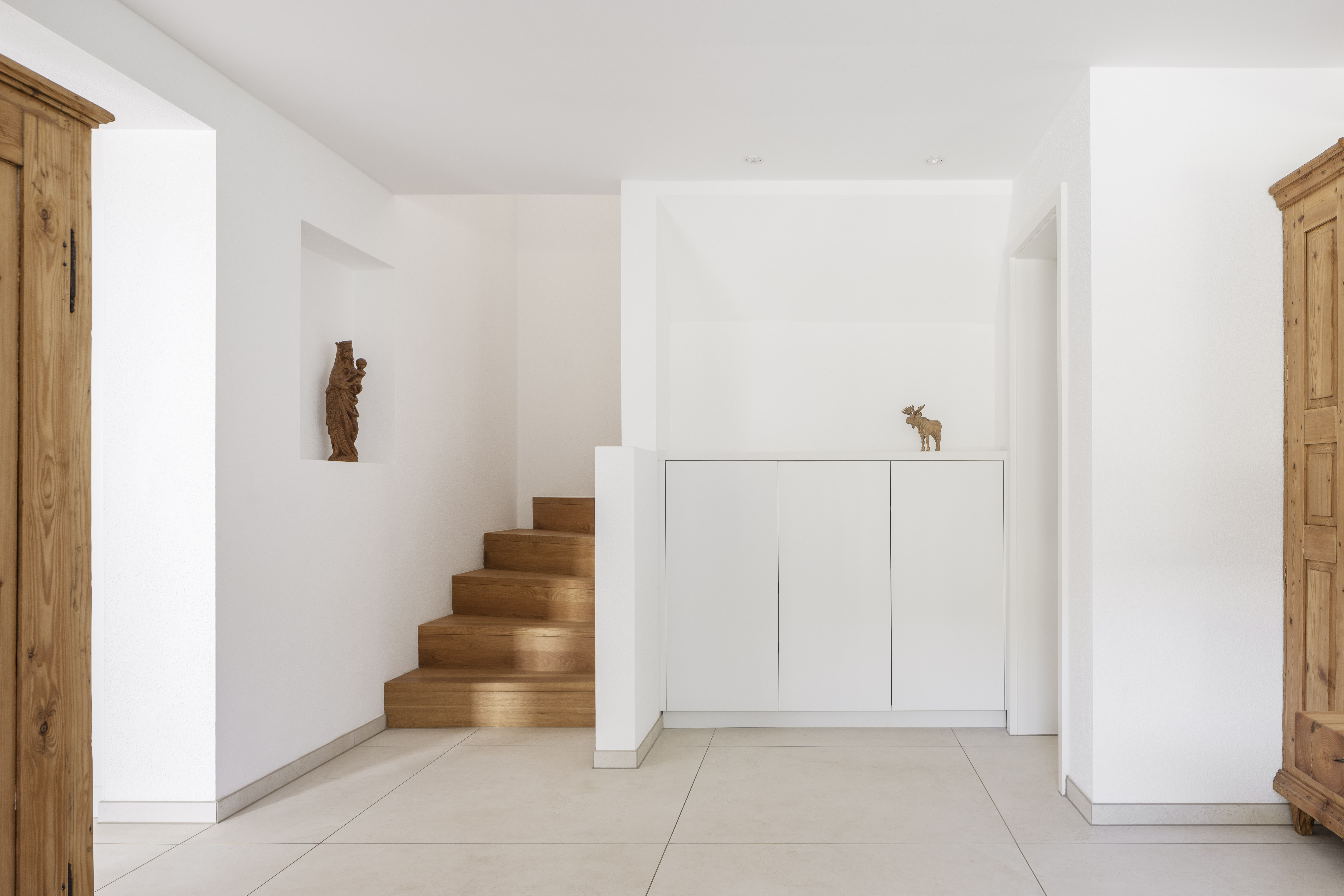 Carreaux de sol clairs et modernes dans une entrée élégante avec escalier en bois.