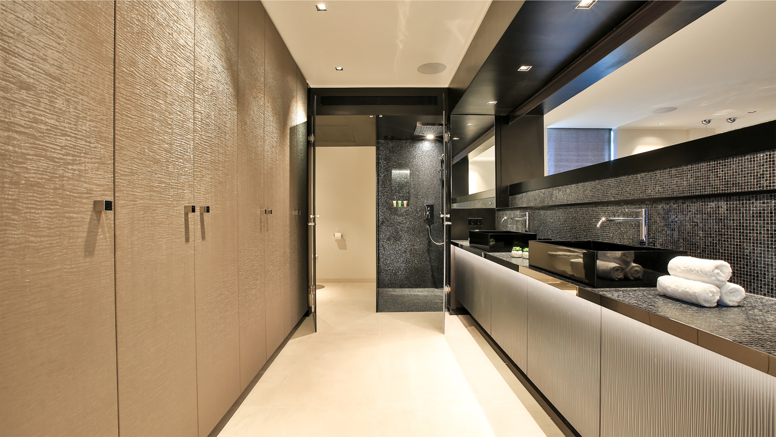 Design de salle de bain haut de gamme avec mosaïques murales foncées et carreaux de sol clairs.