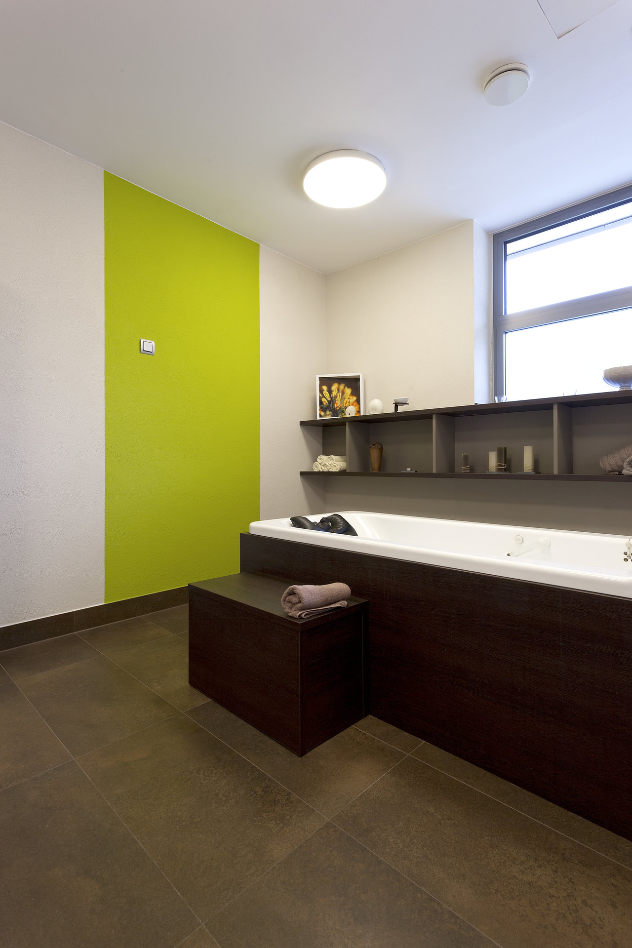 Salle de bain moderne avec carrelage de sol foncé grand format et mur d'accent vert.