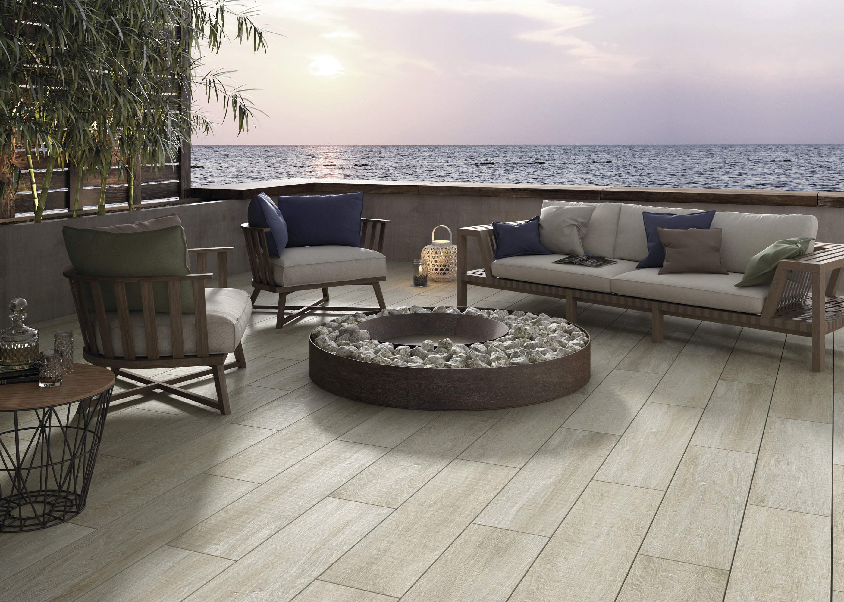 Terrasse avec carreaux aspect bois clair, canapé lounge et vue mer au coucher du soleil.