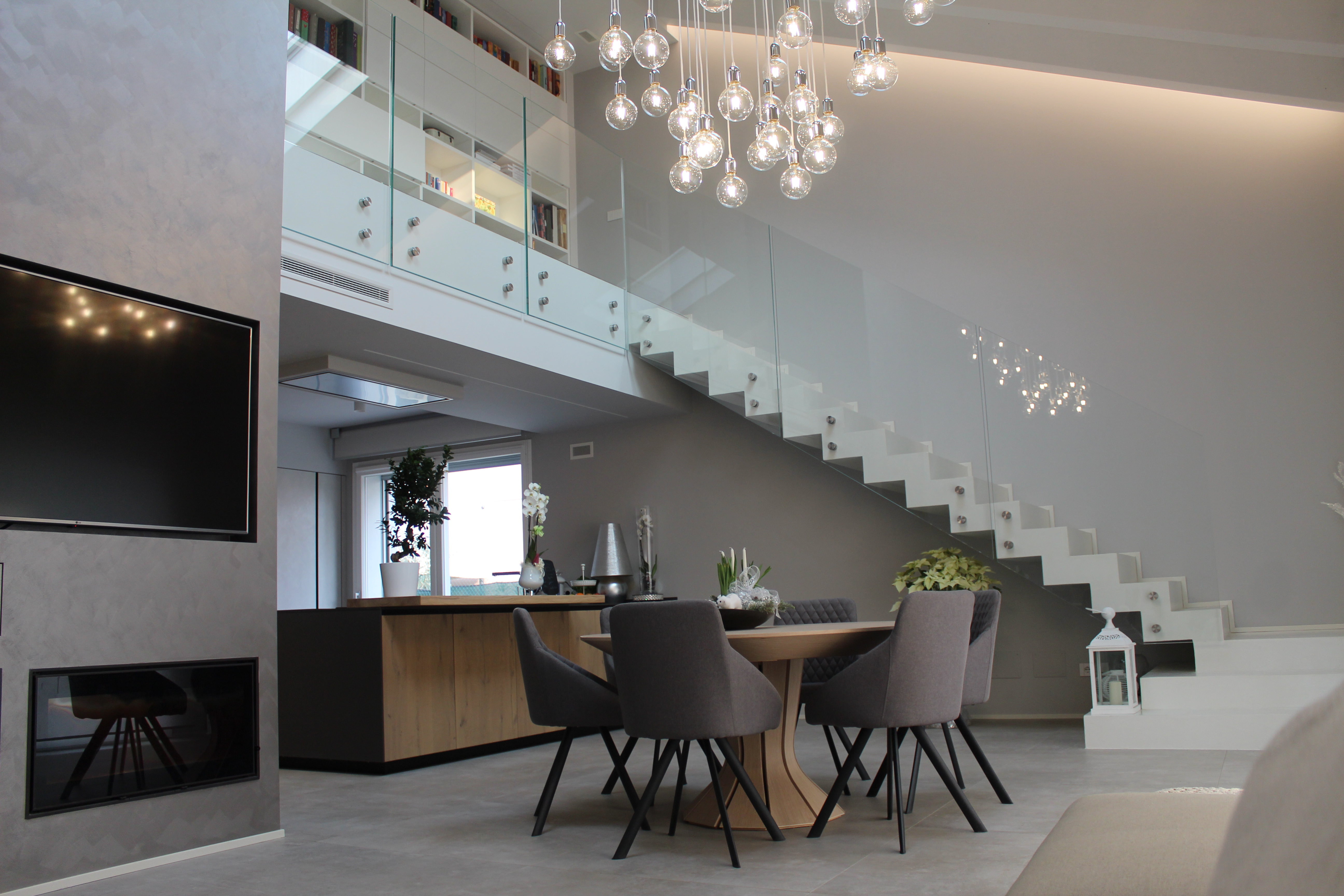 Espace de vie moderne avec de grands carreaux gris, coin repas et galerie ouverte.
