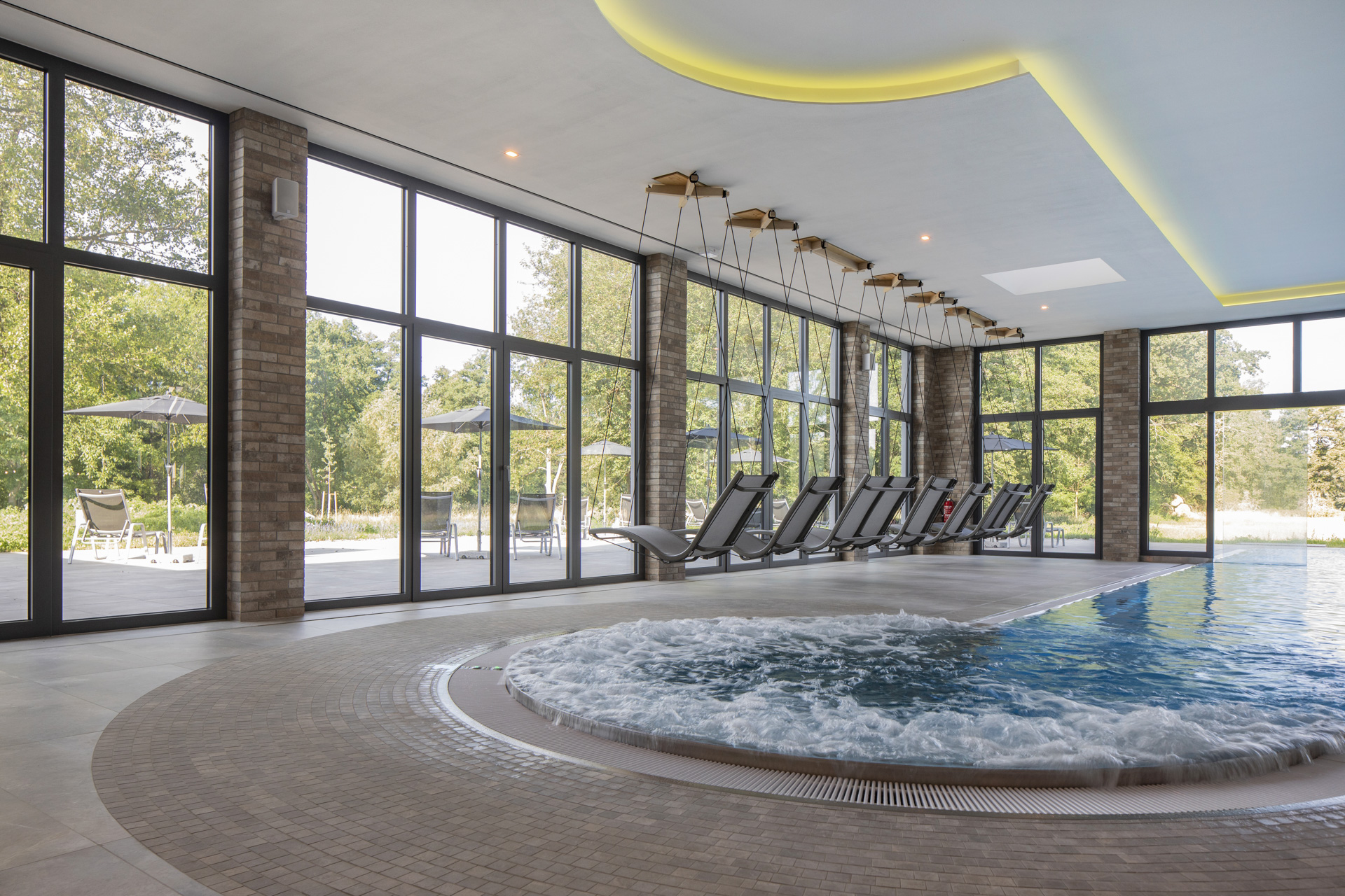 Piscine intérieure exclusive avec bain à remous et carreaux élégants aspect brique et pierre naturelle.
