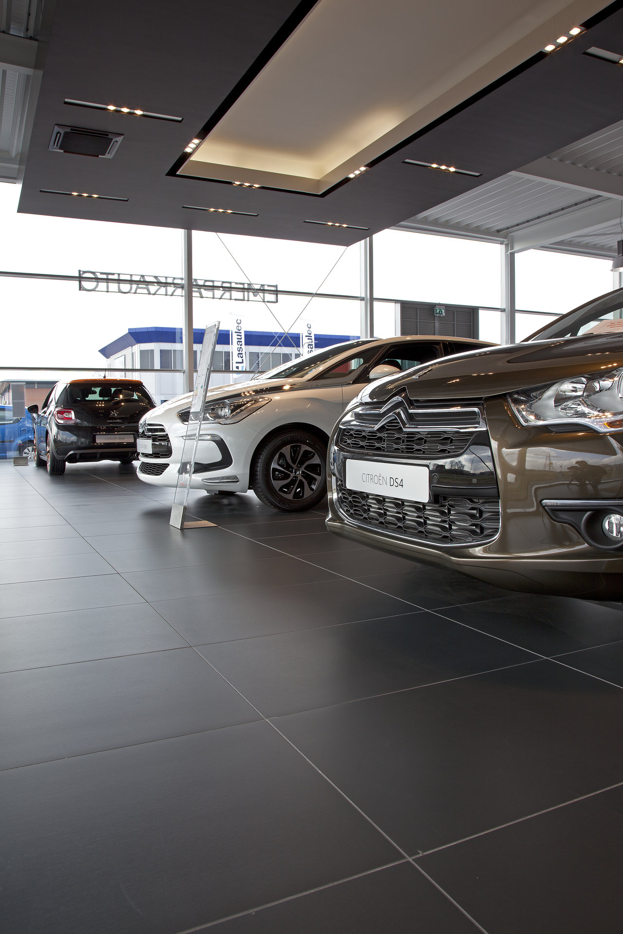 Carreaux grand format anthracite haut de gamme en showroom automobile.