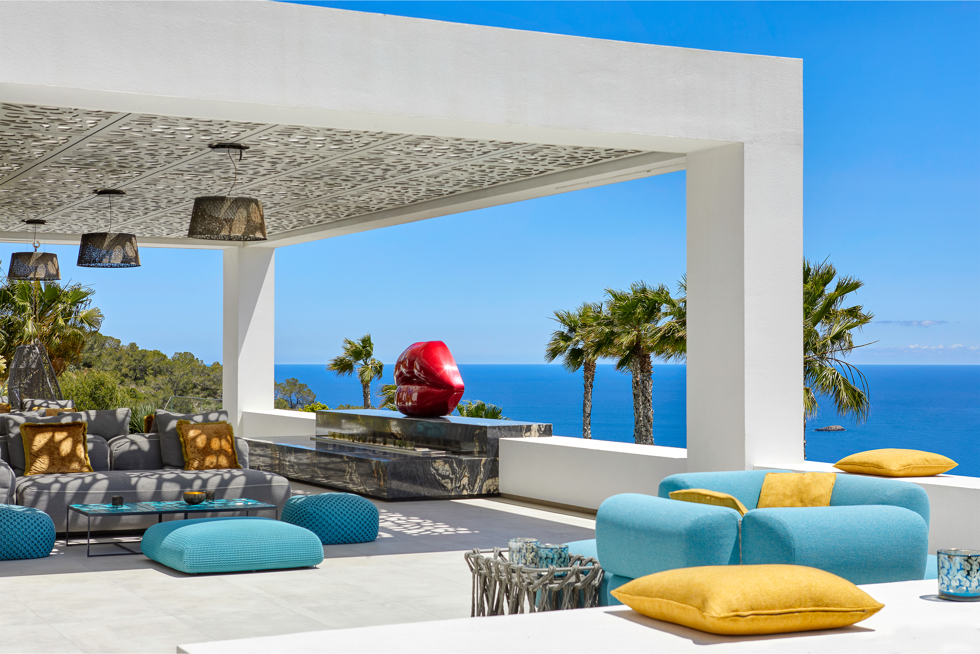 Lounge extérieur moderne sur terrasse carrelée avec vue sur mer.