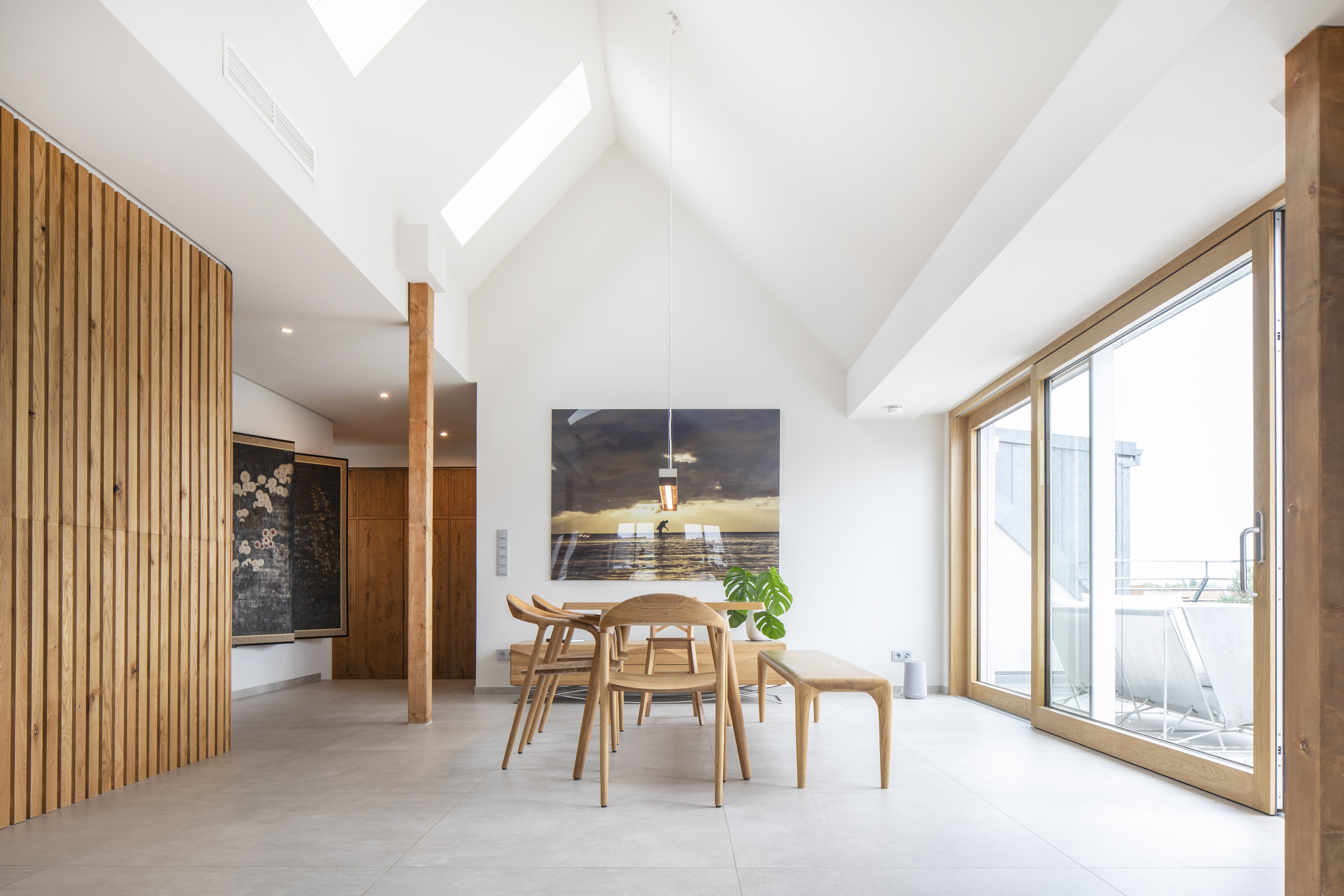 Lumineux coin repas avec carrelage grand format, accents bois et accès terrasse.