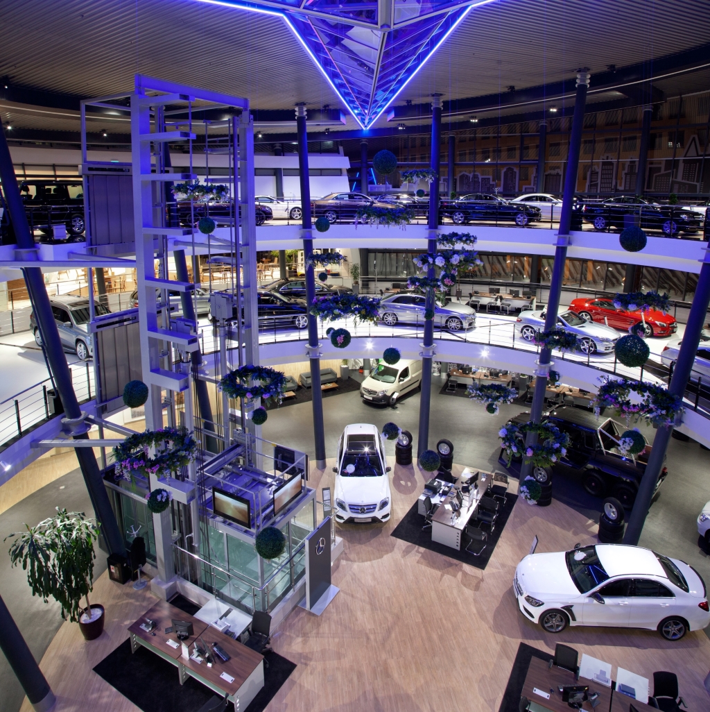 Showroom auto moderne multi-étages avec éclairage bleu et de nombreuses voitures.