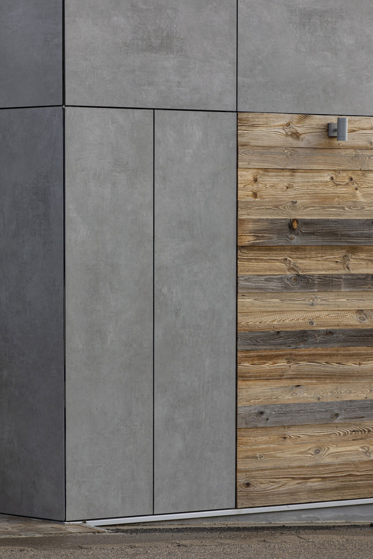 Façade moderne avec carreaux gris effet béton et panneaux de bois rustiques.