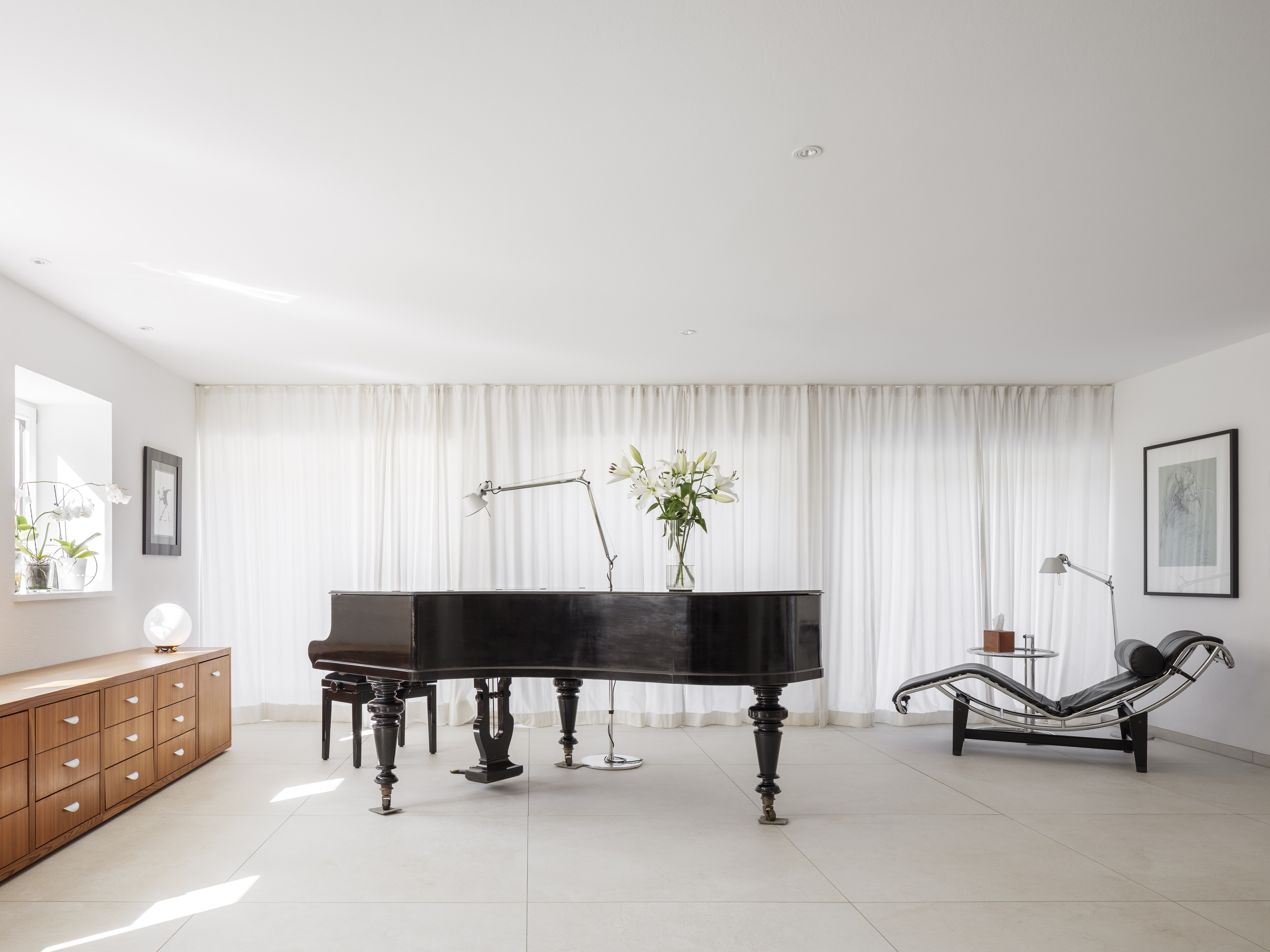Espace lumineux et moderne avec carrelage grand format, piano à queue et mobilier design.