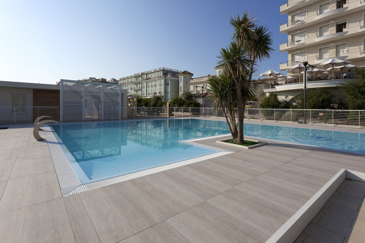 Carreaux d'extérieur de haute qualité en gris clair autour d'une élégante piscine.