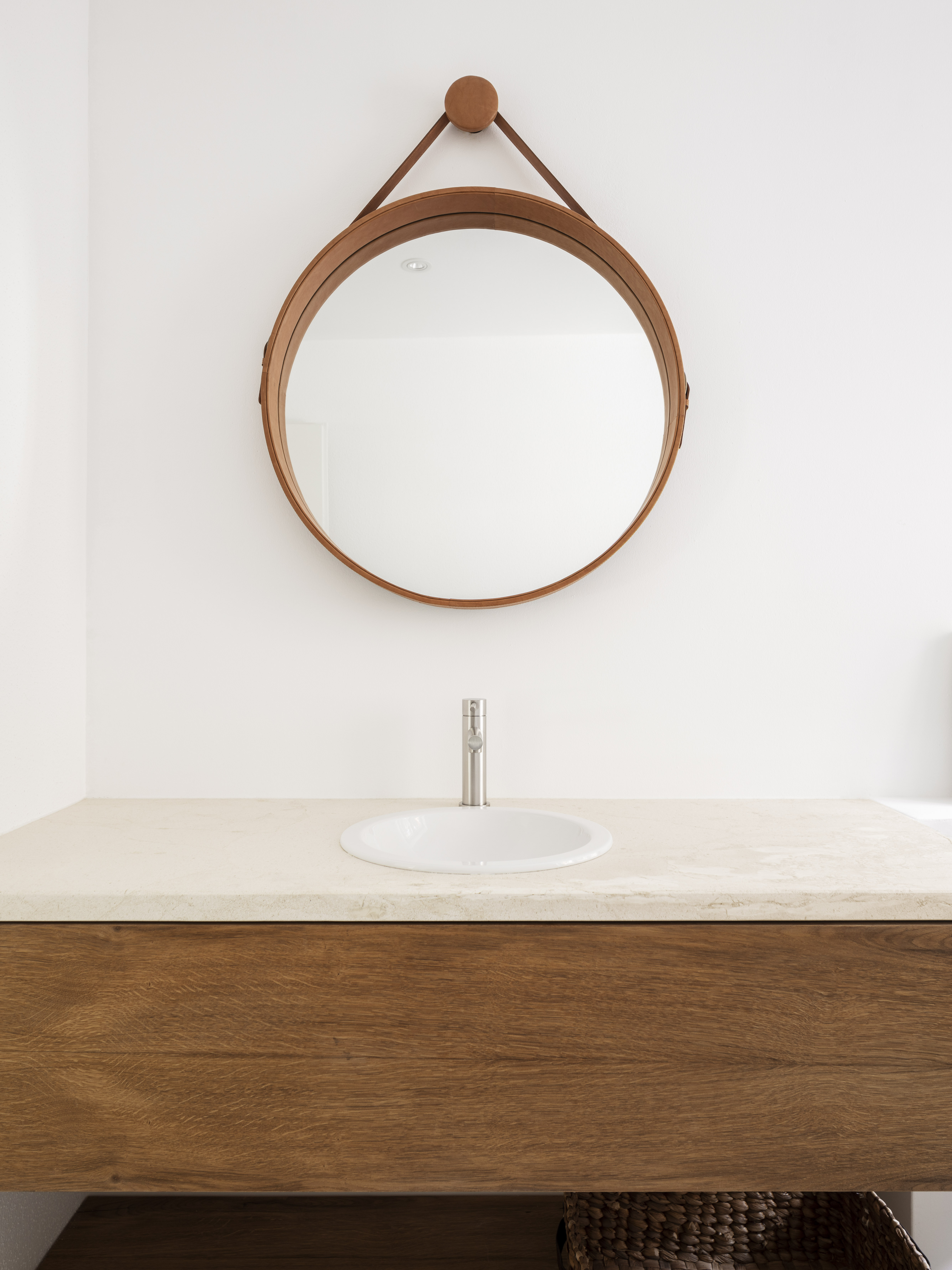 Salle de bain moderne avec vasque sur meuble en bois et miroir rond en bois.