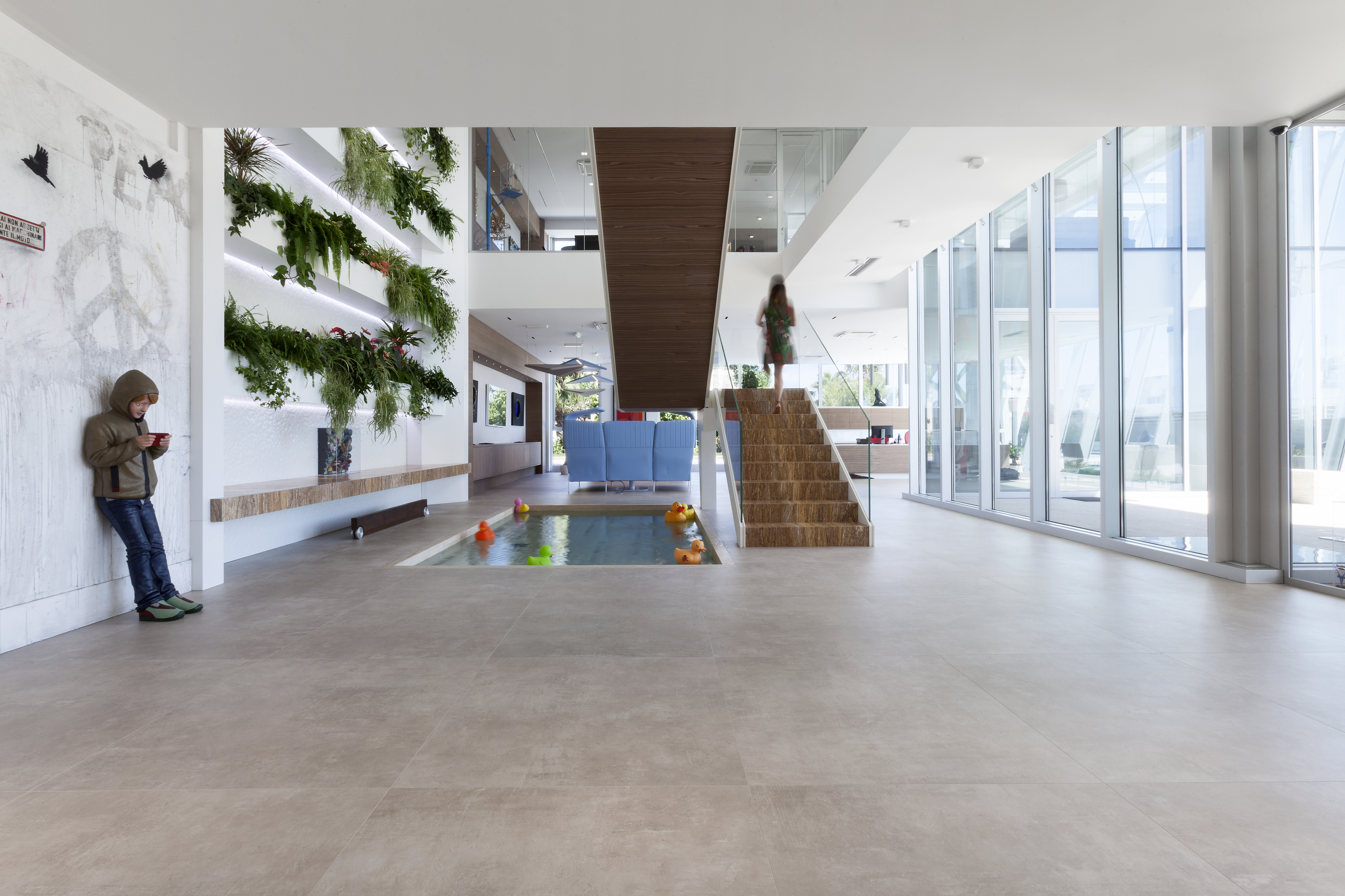 Intérieur spacieux et lumineux avec carrelage moderne, escalier en bois et jardin vertical.