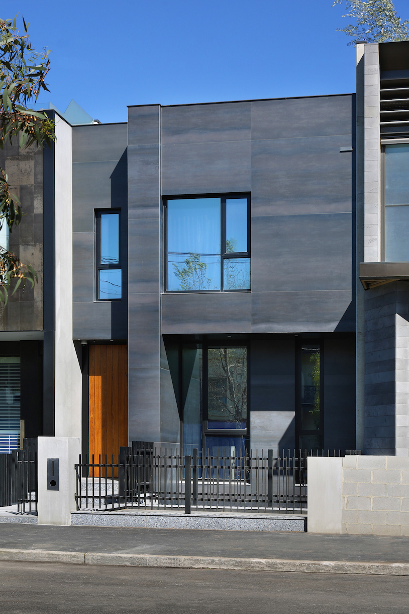 Façade de maison moderne avec carreaux foncés de haute qualité et porte en bois.