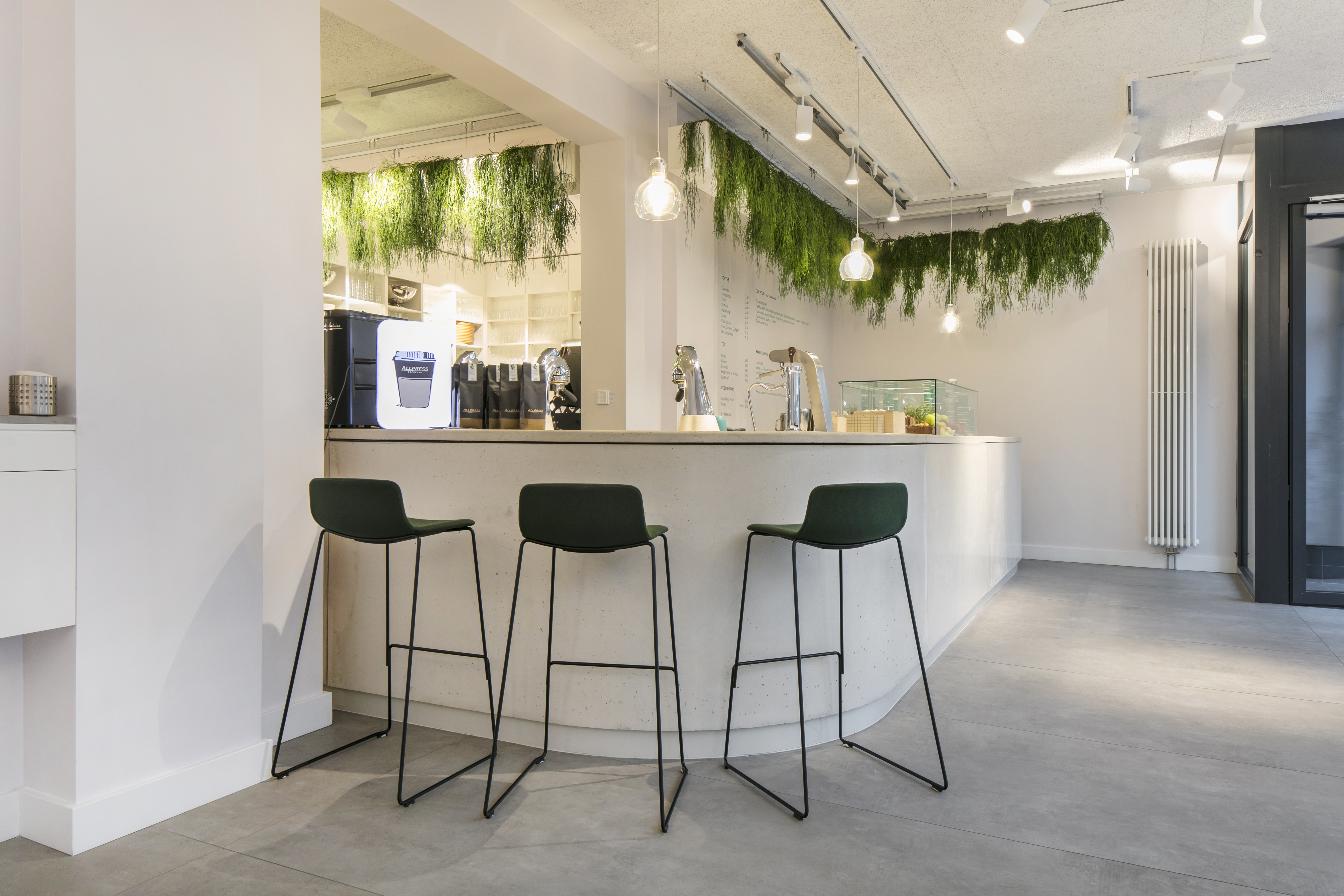 Zone de réception lumineuse et moderne avec carrelage aspect béton et bar élégant.