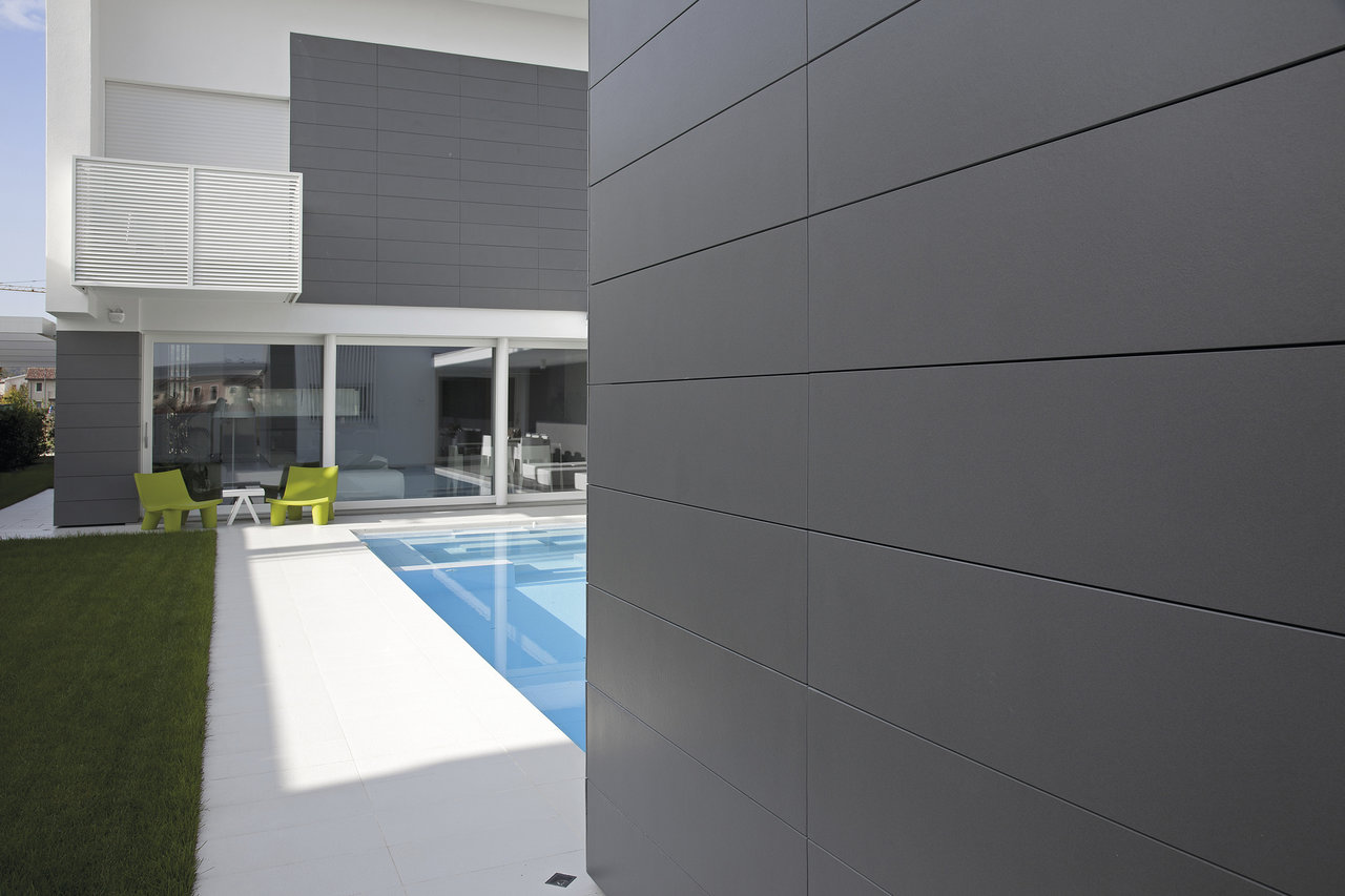 Carreaux extérieurs gris foncé sur façade de maison moderne et contour de piscine.