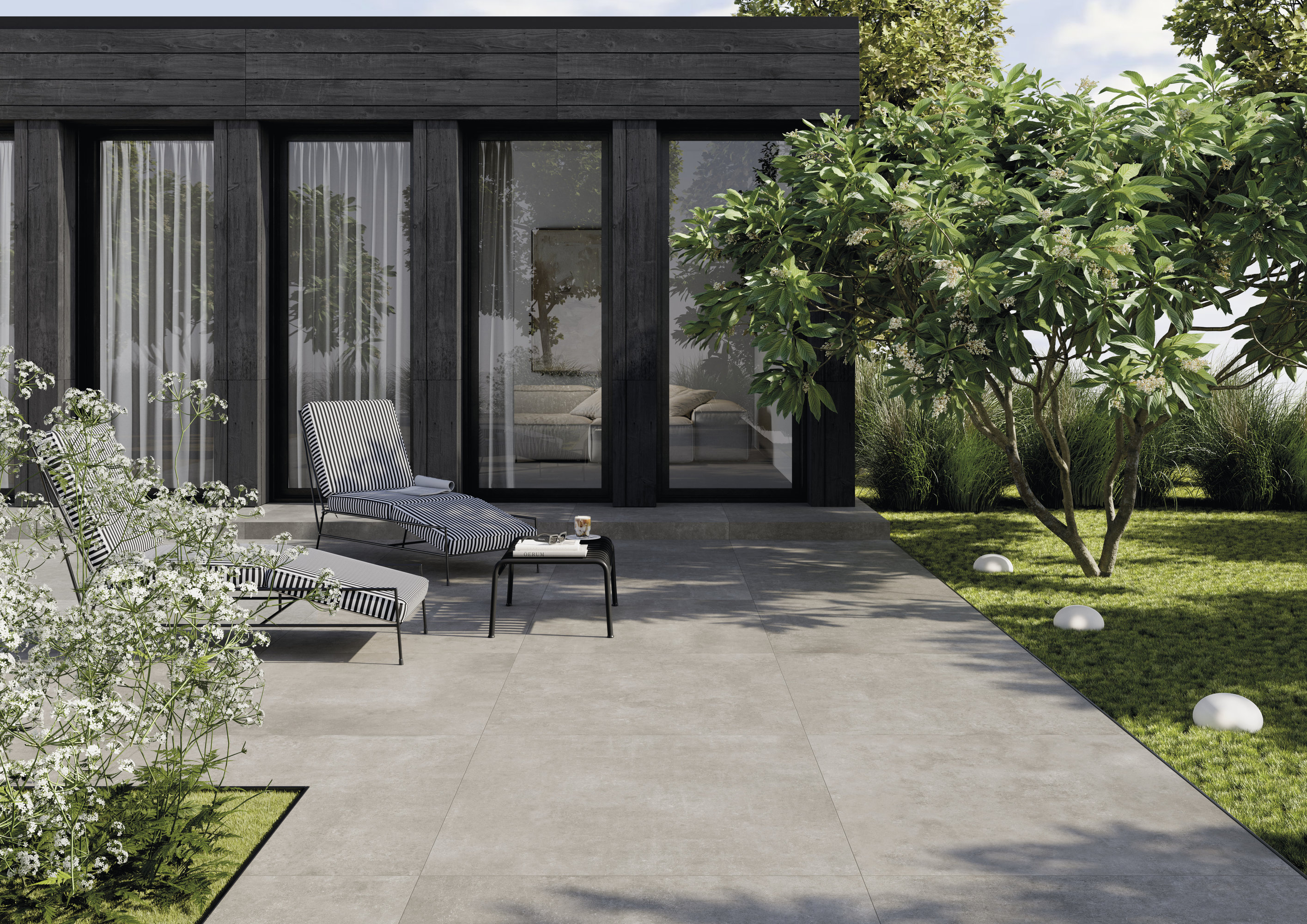 Moderne Terrasse mit hellgrauen Outdoor-Fliesen, Liegestühlen und Garten.