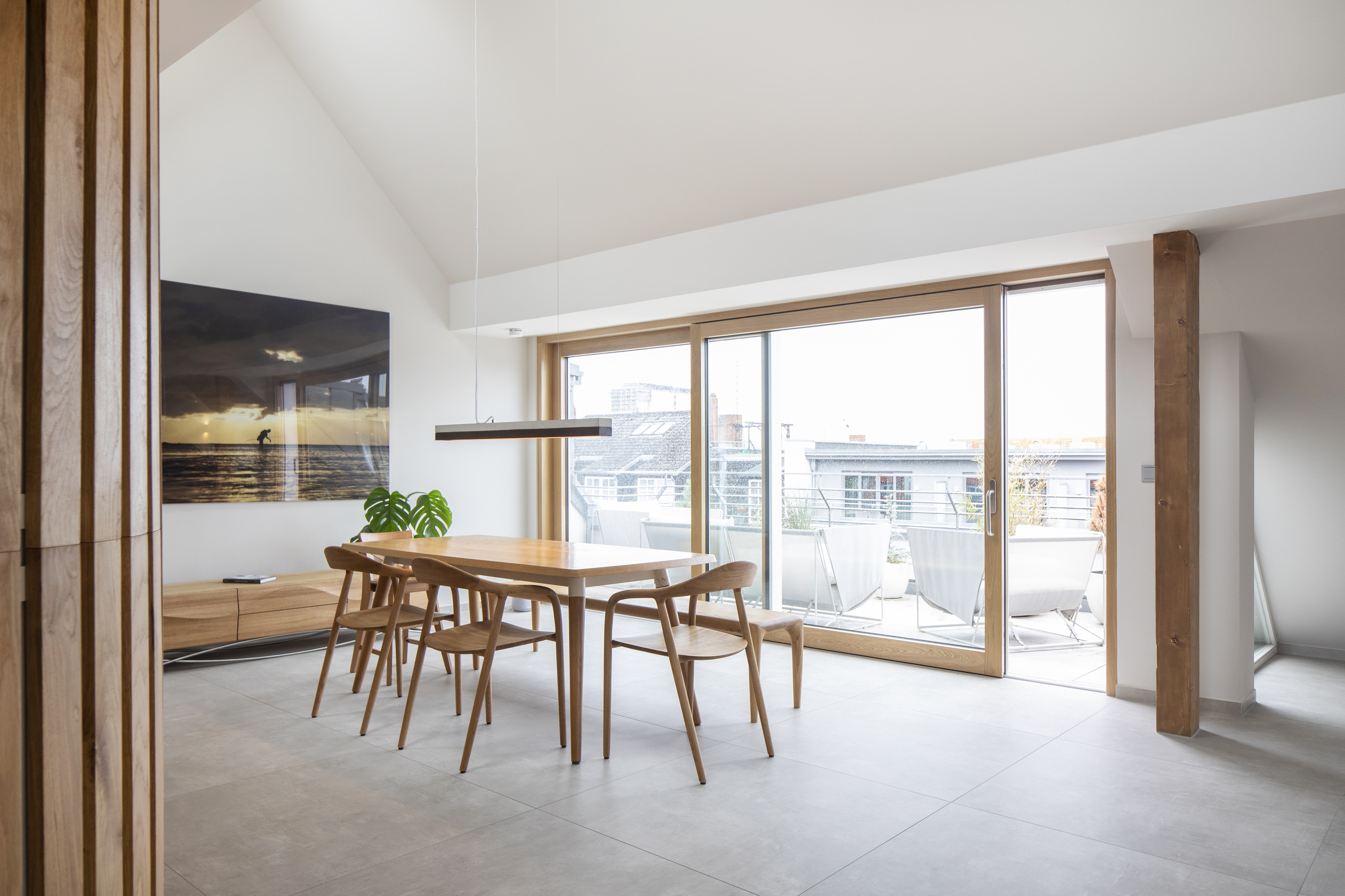 Salle à manger moderne avec carrelage gris clair et accès terrasse.