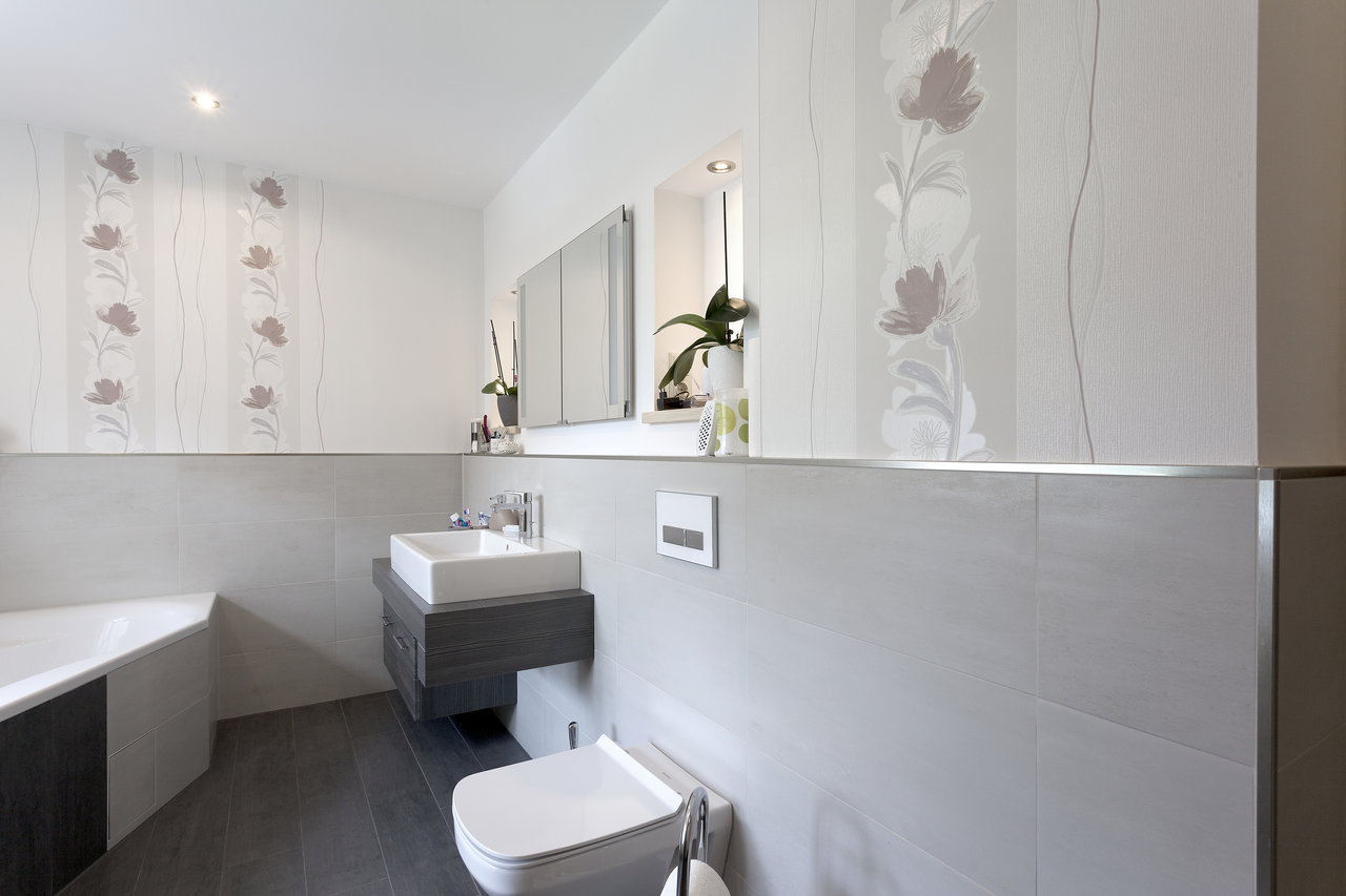 Salle de bain élégante avec carrelage mural clair et carrelage au sol foncé.