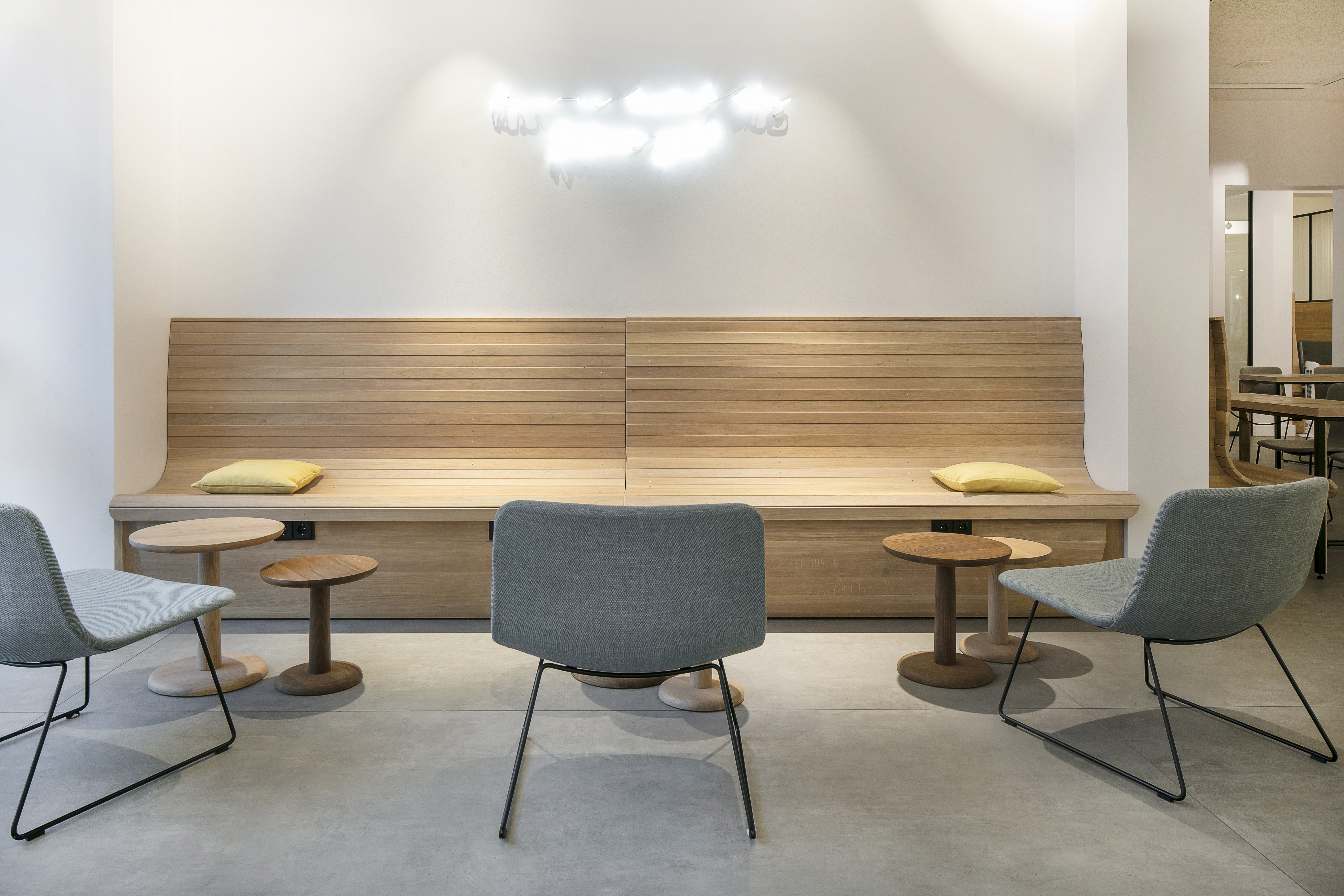 Intérieur lumineux avec carrelage moderne, banc en bois et chaises grises.