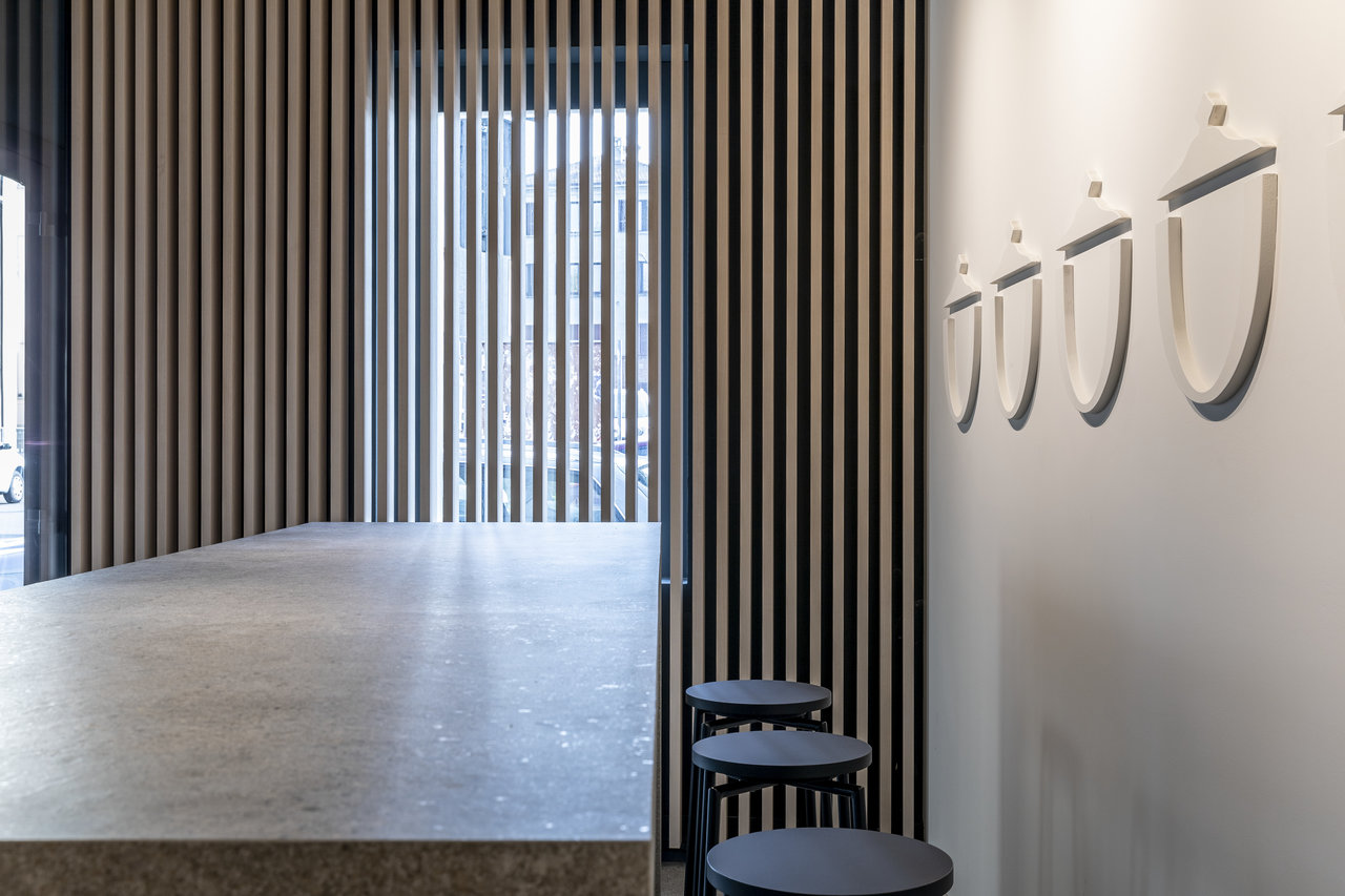 Espace moderne avec carrelage effet béton clair et lamelles de bois verticales au mur.