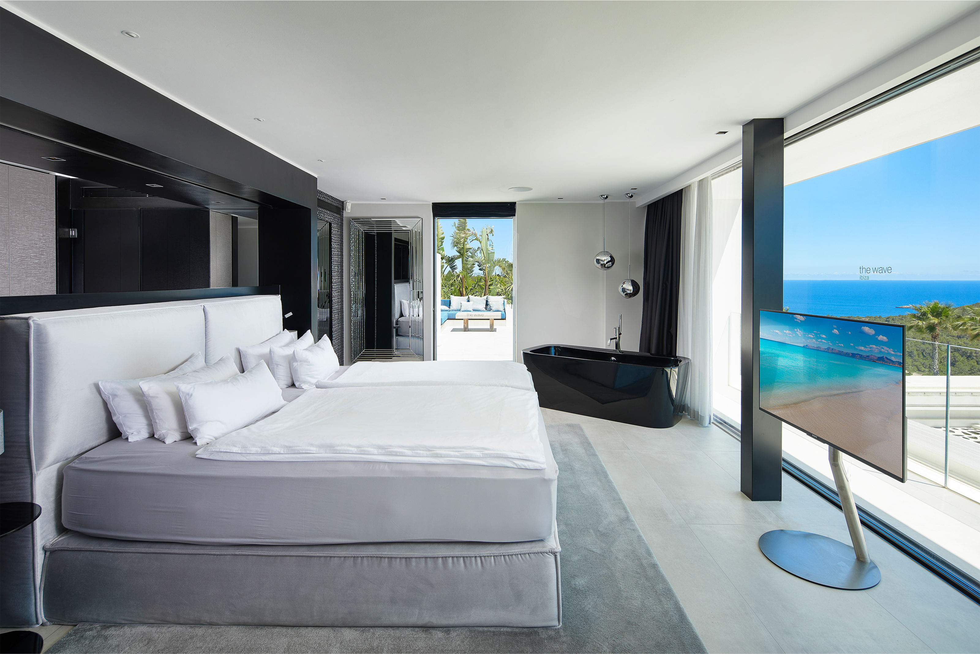 Chambre avec vue mer, baignoire îlot et carrelage de sol clair et moderne.