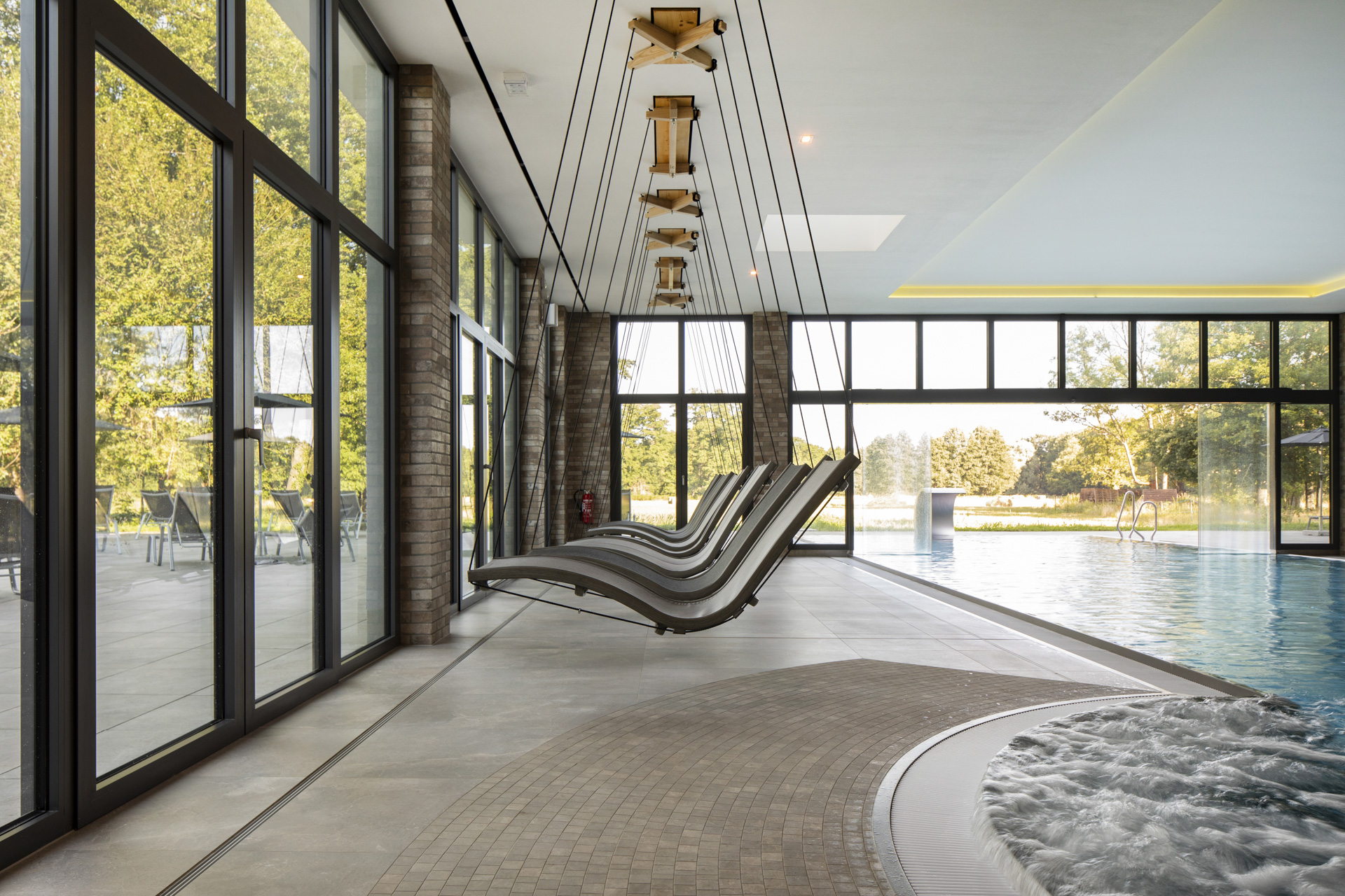 Espace bien-être moderne avec carrelage grand format, piscine, jacuzzi et fenêtres panoramiques.