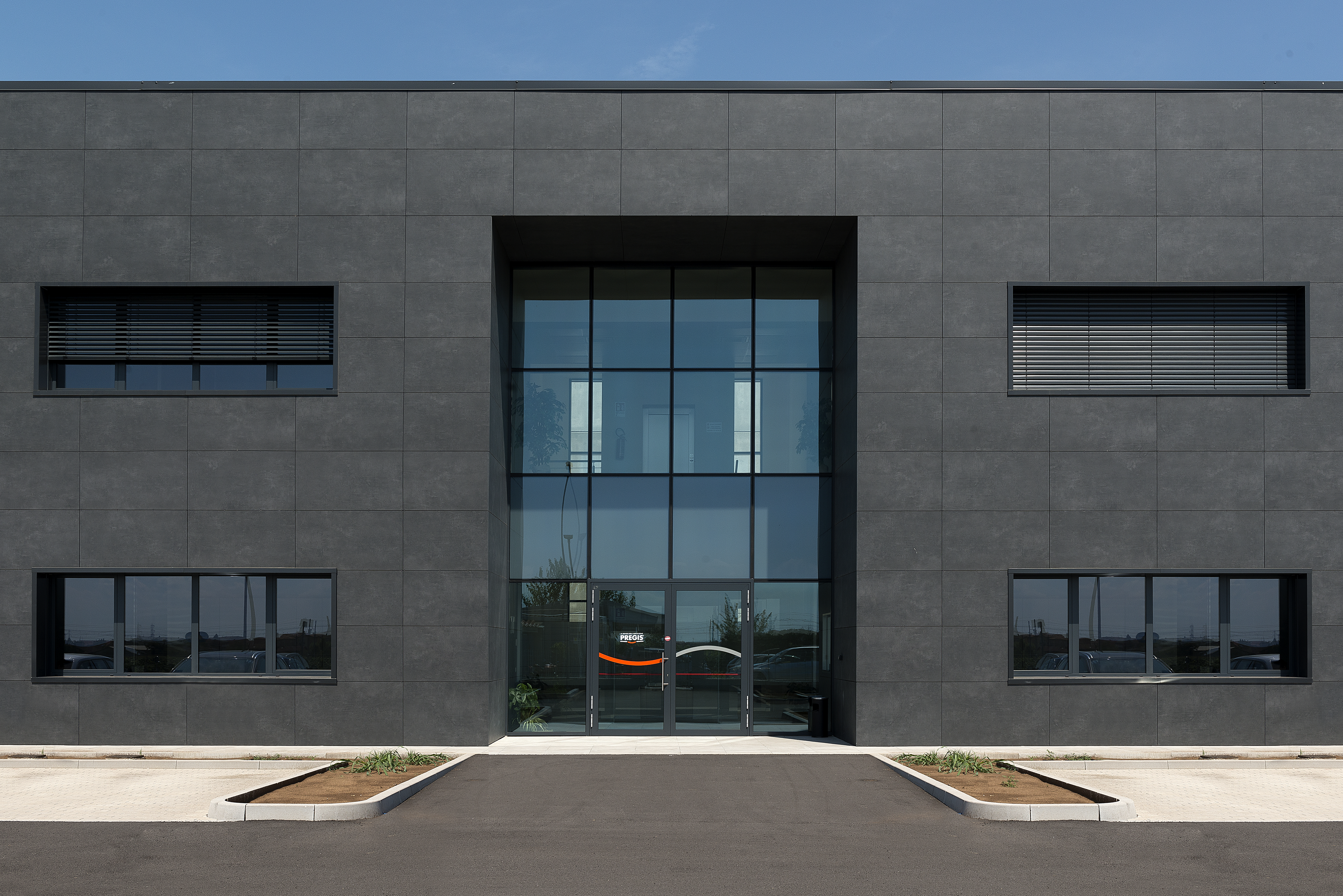 Façade moderne avec revêtement extérieur haut de gamme en grandes dalles de porcelaine foncée.