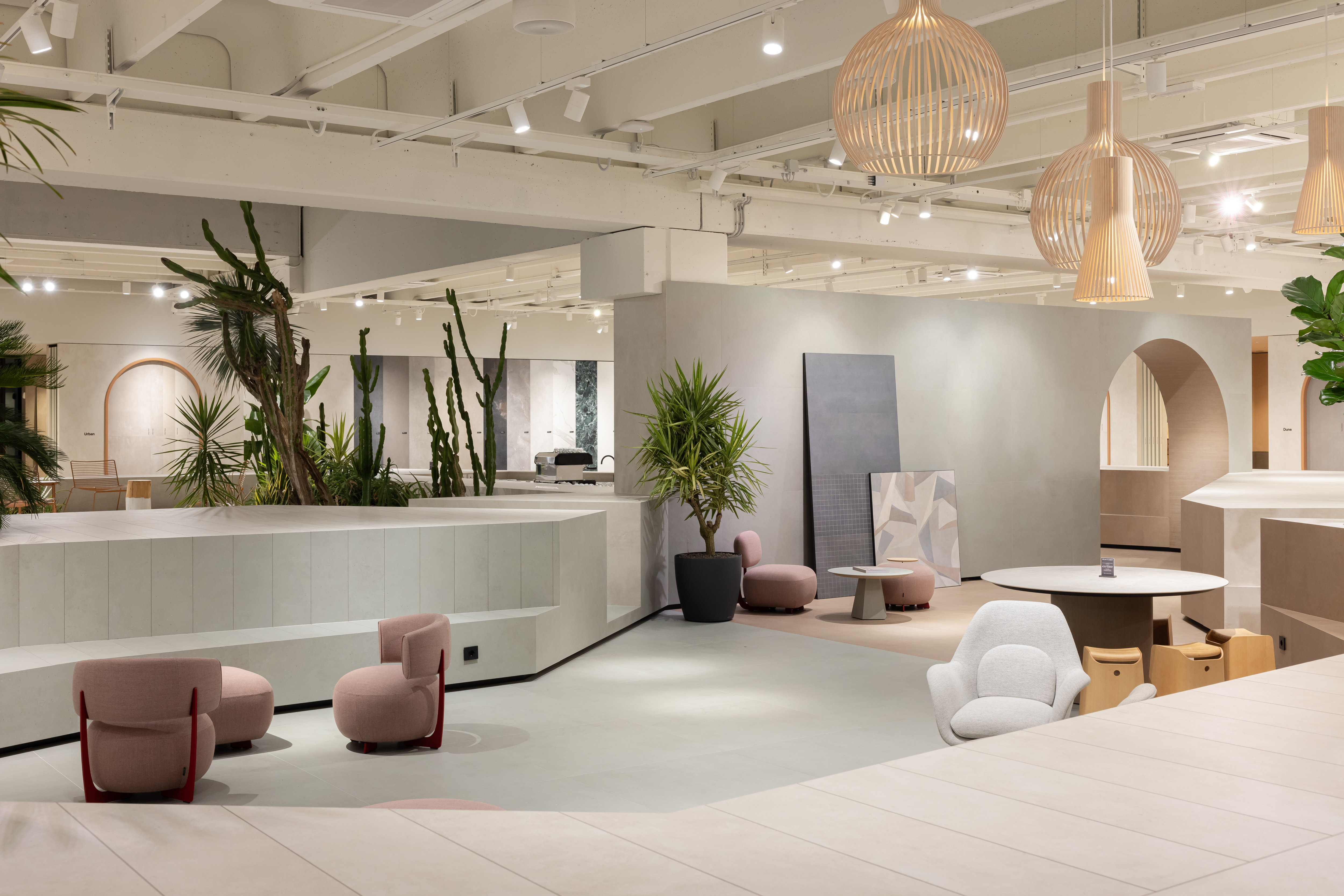 Showroom de carrelage lumineux et moderne avec coins salon élégants et plantes.