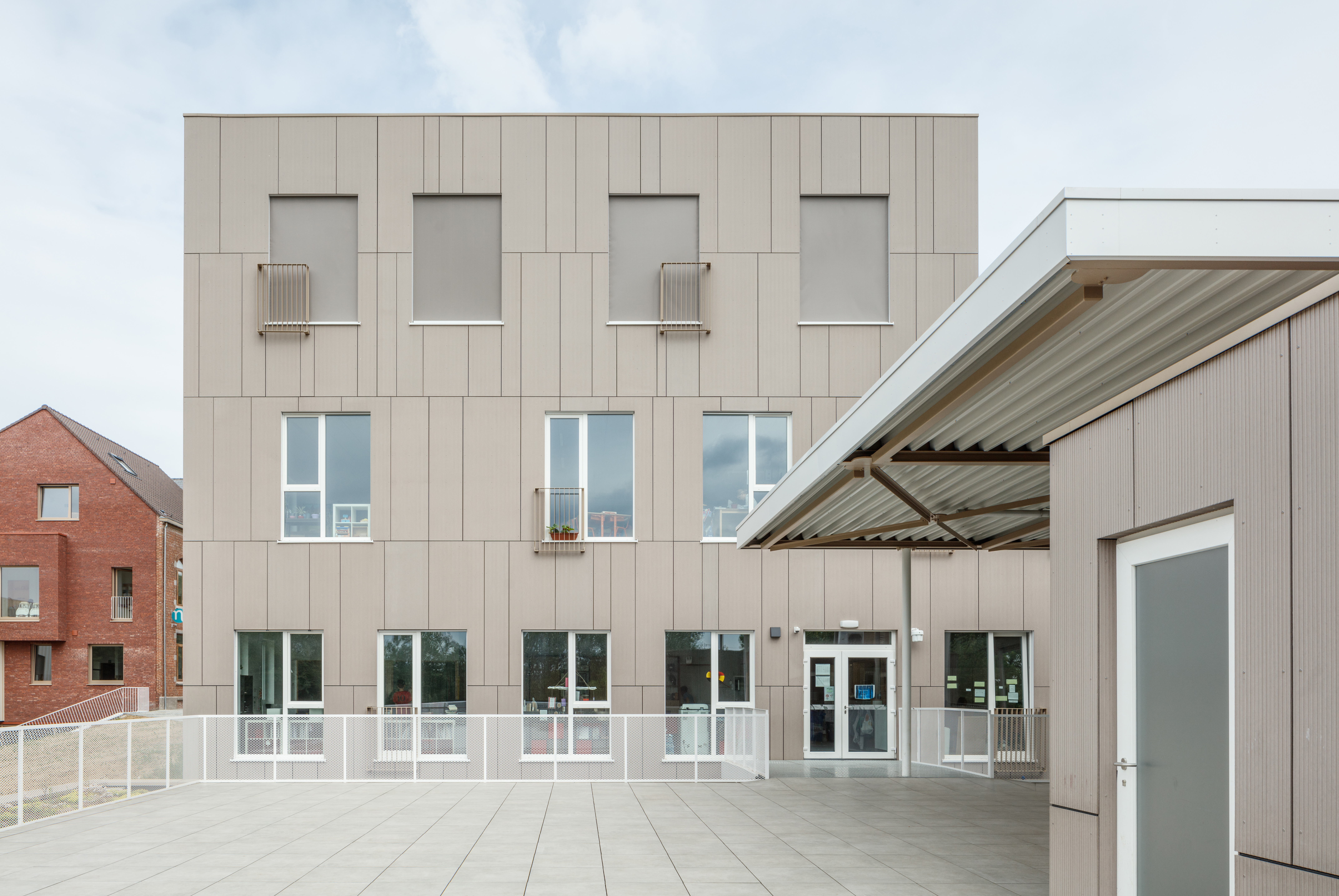 Dalles de terrasse en beige clair devant un bâtiment moderne.