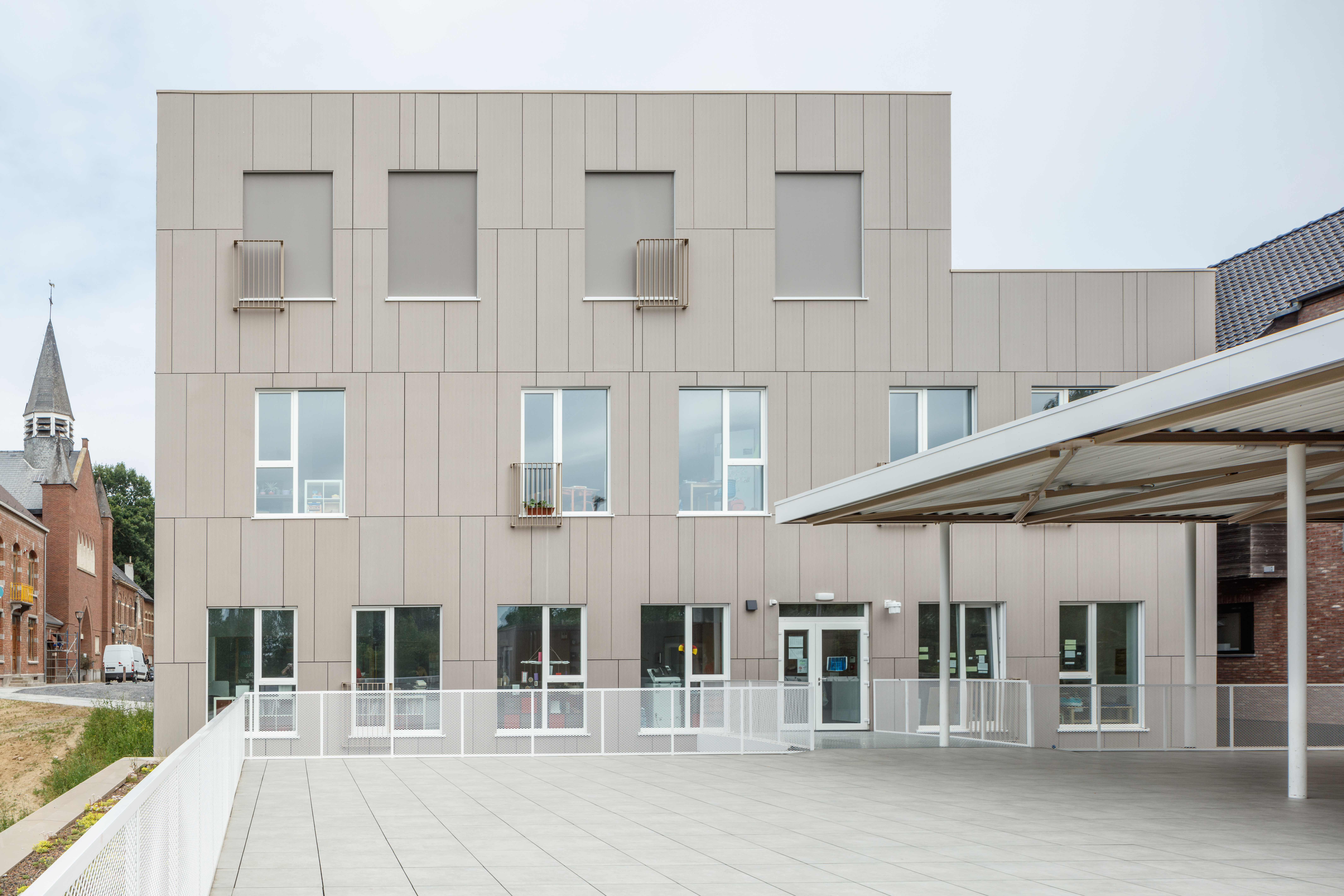 Dalles d'extérieur claires grand format sur terrasse devant bâtiment moderne.