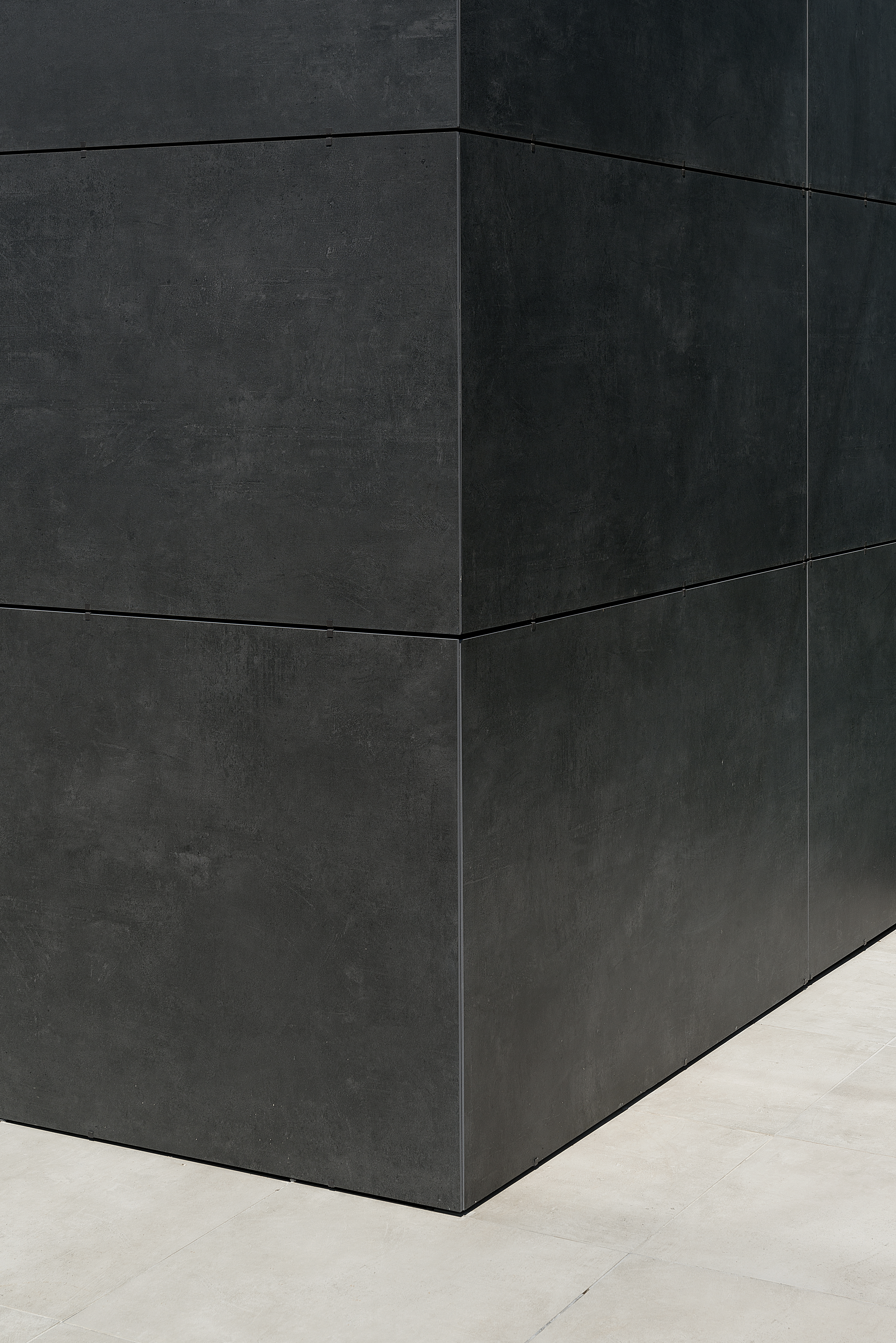 Carreaux grand format gris foncé aspect béton pour intérieurs et extérieurs modernes.