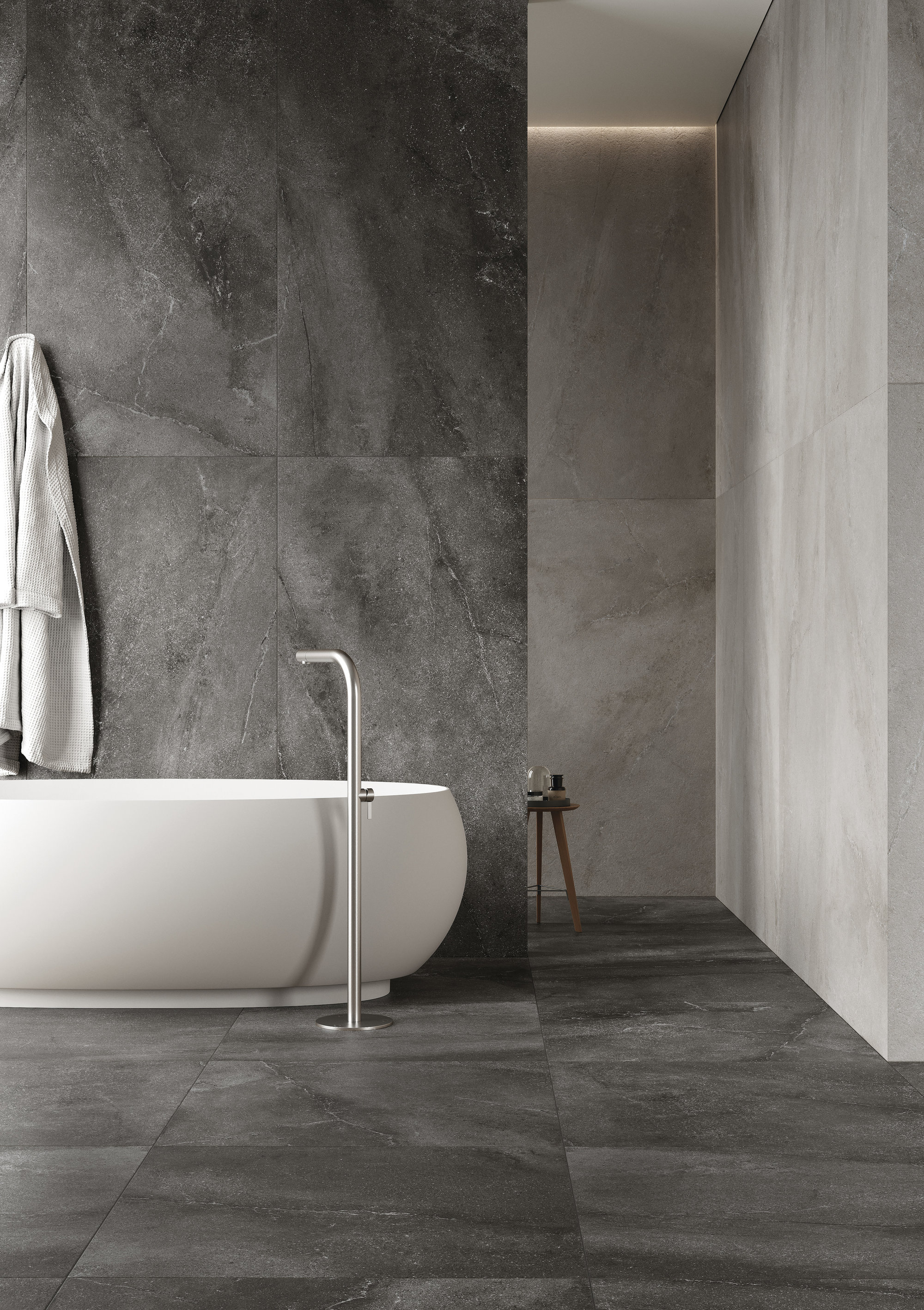 Salle de bain élégante avec carrelage grand format gris foncé et baignoire îlot moderne.