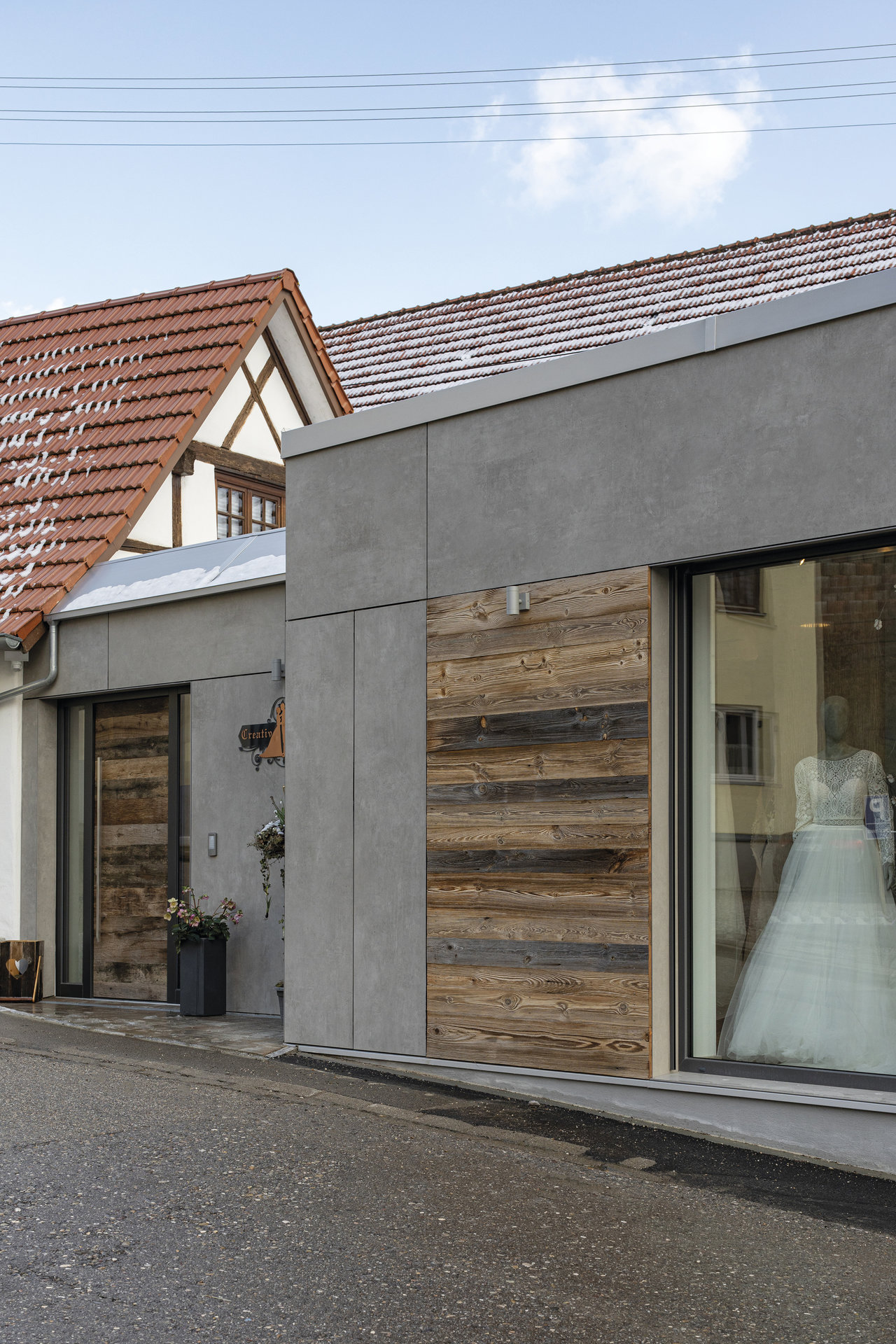 Façade contemporaine avec de grandes dalles grises et des accents de bois ancien.