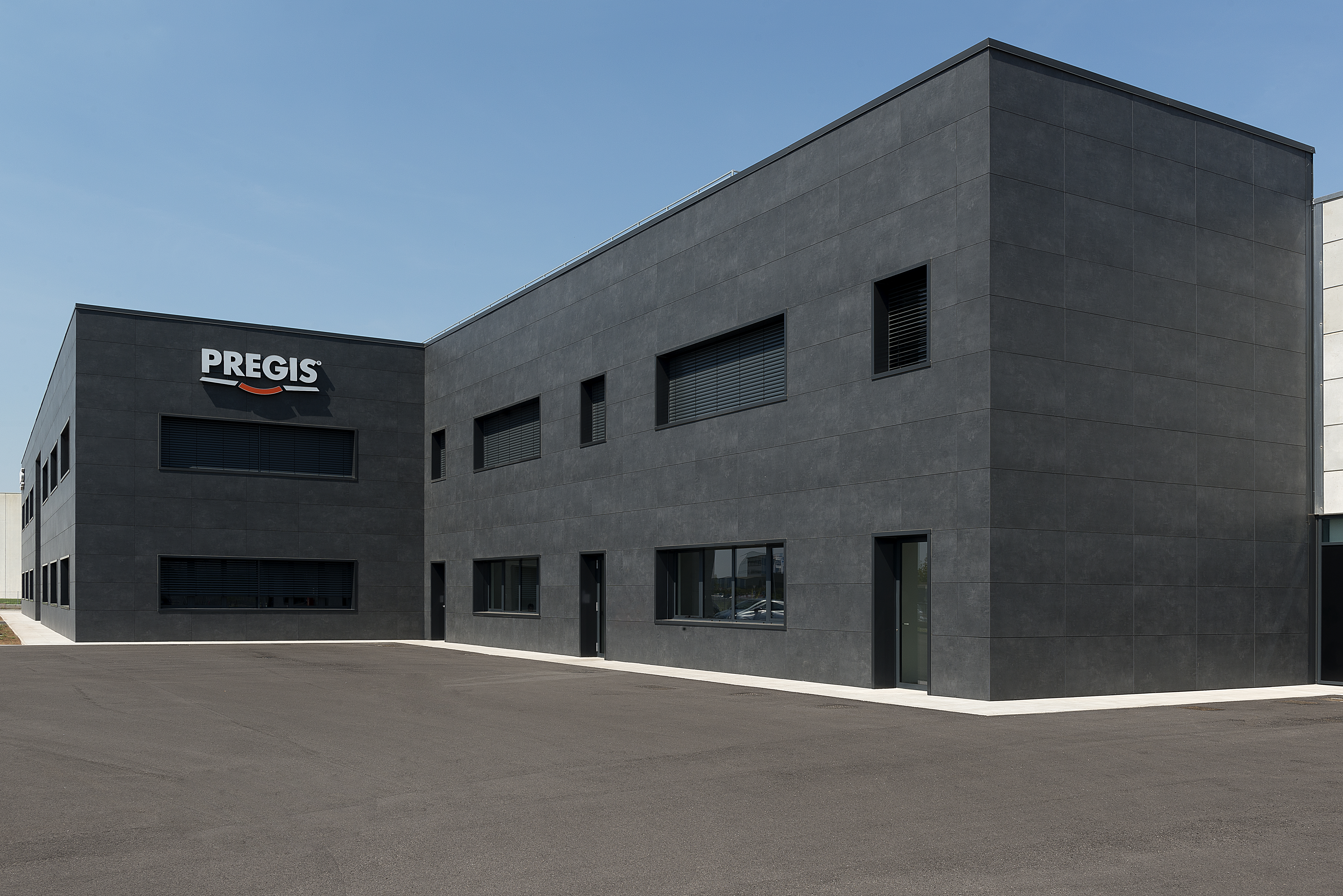 Bâtiment moderne gris foncé avec logo PREGIS et grand parvis.