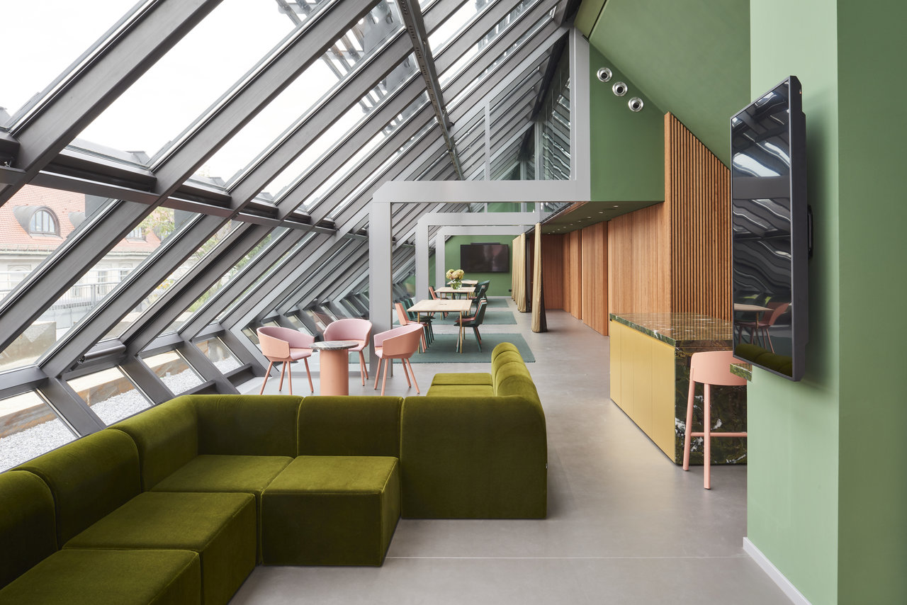 Pièce moderne et lumineuse avec carrelage grand format, coin lounge vert et façade vitrée.