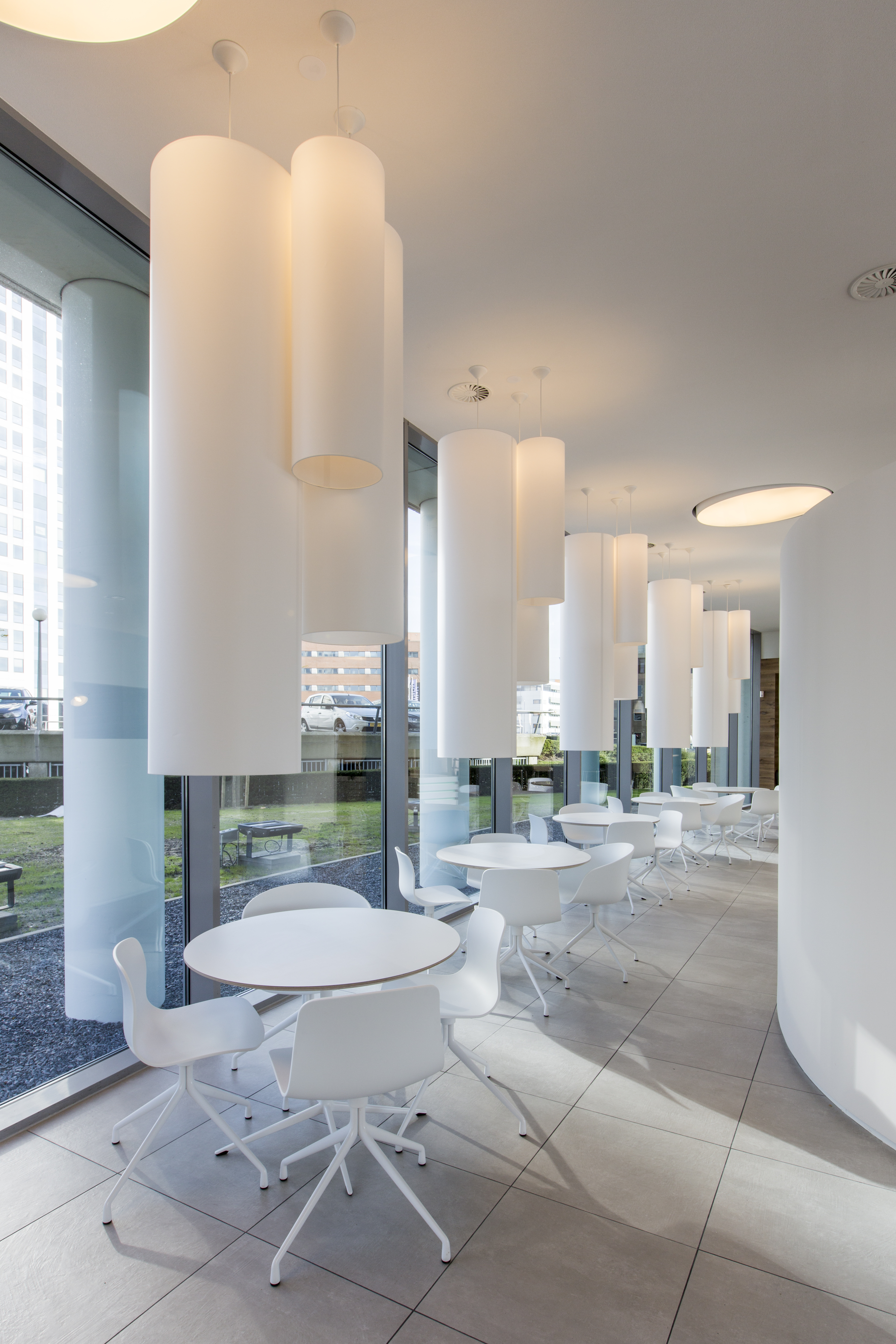 Lounge moderne avec carrelage gris clair, tables blanches et design minimaliste.