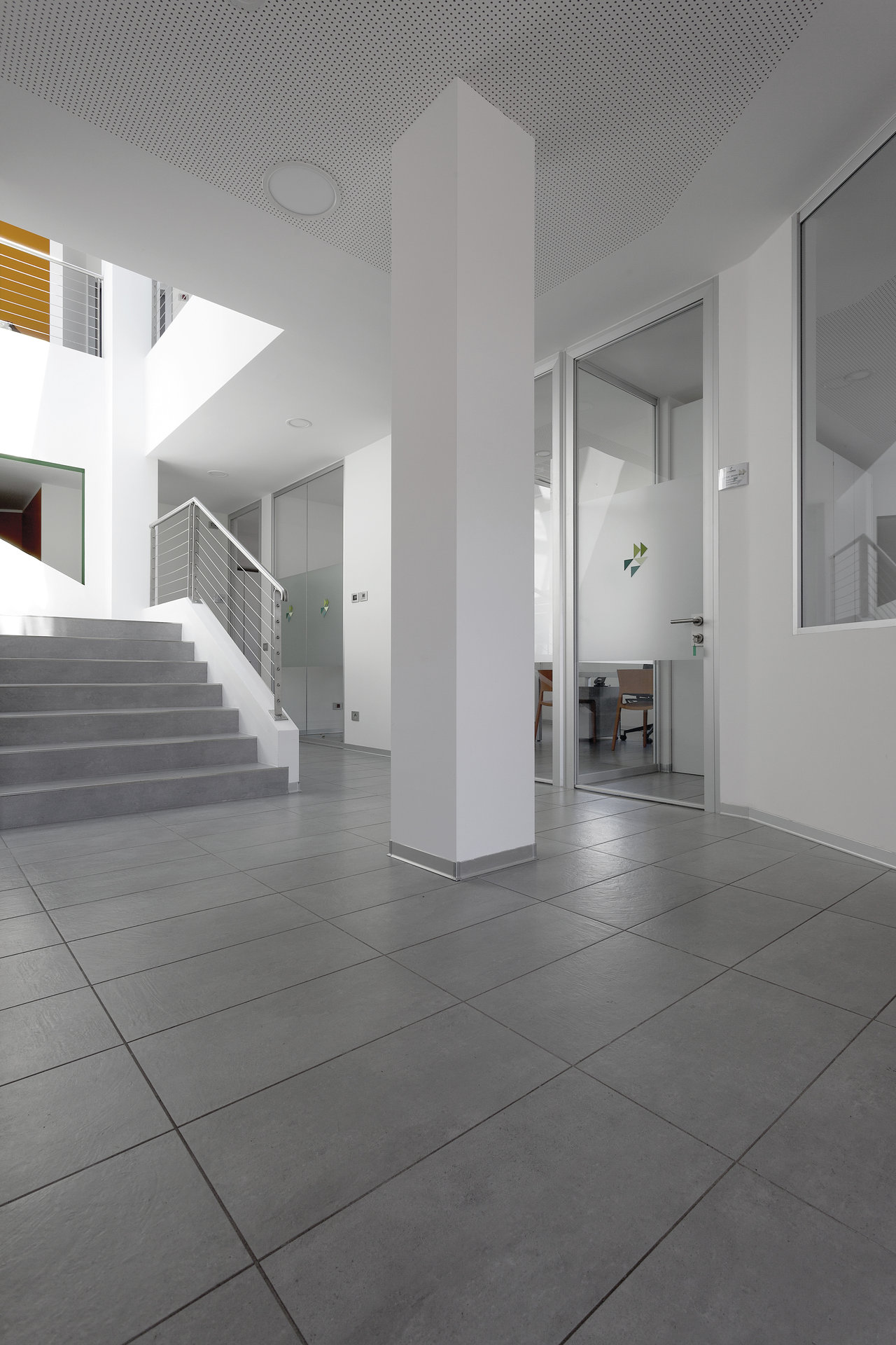 Carrelage de sol gris grand format dans un foyer lumineux et moderne avec escalier.