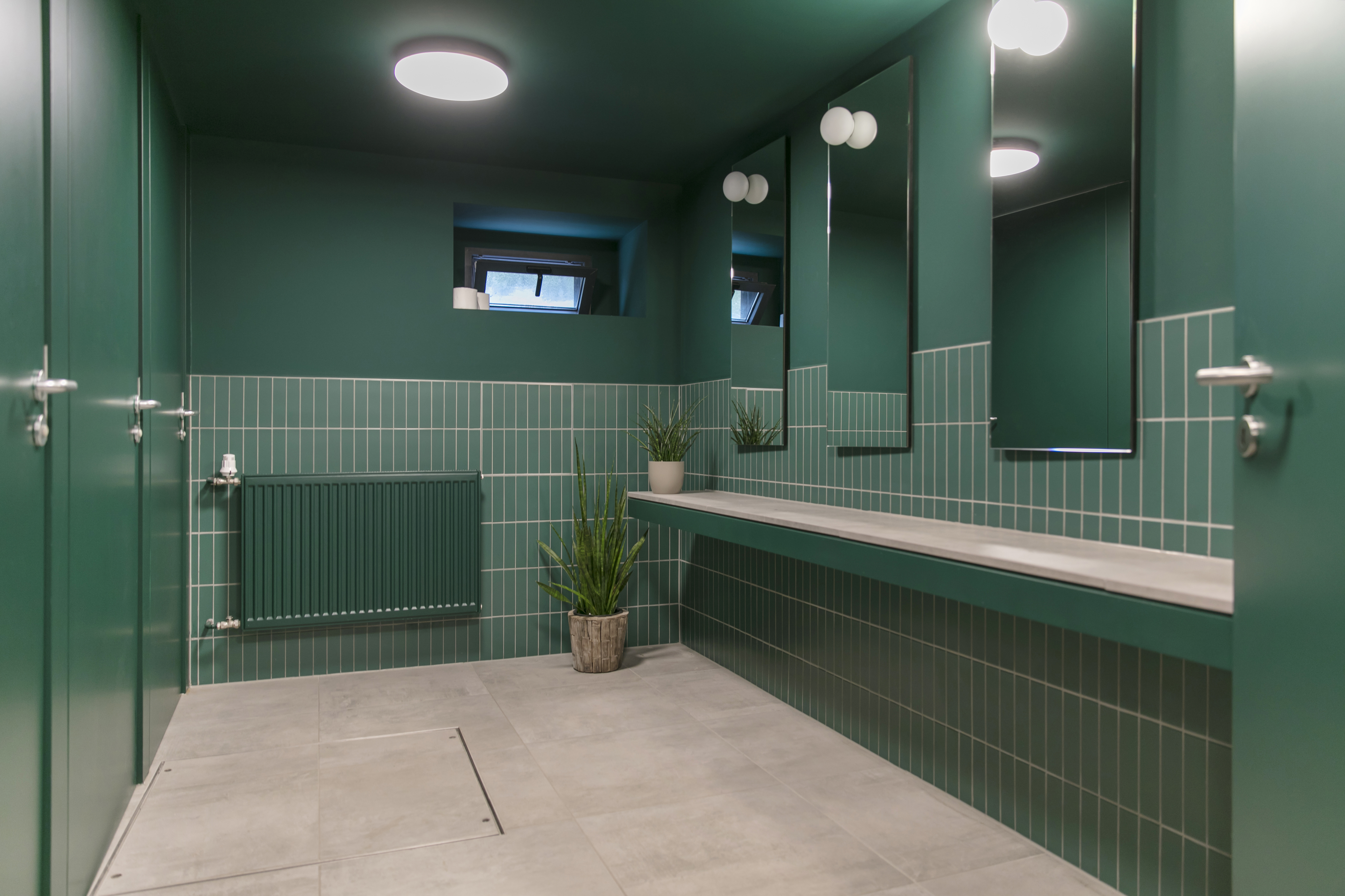 Salle de bain élégante avec carreaux muraux verts et carreaux de sol gris.