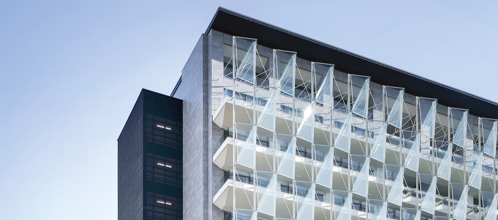 Façade moderne avec des éléments triangulaires en verre et structurés distinctifs.
