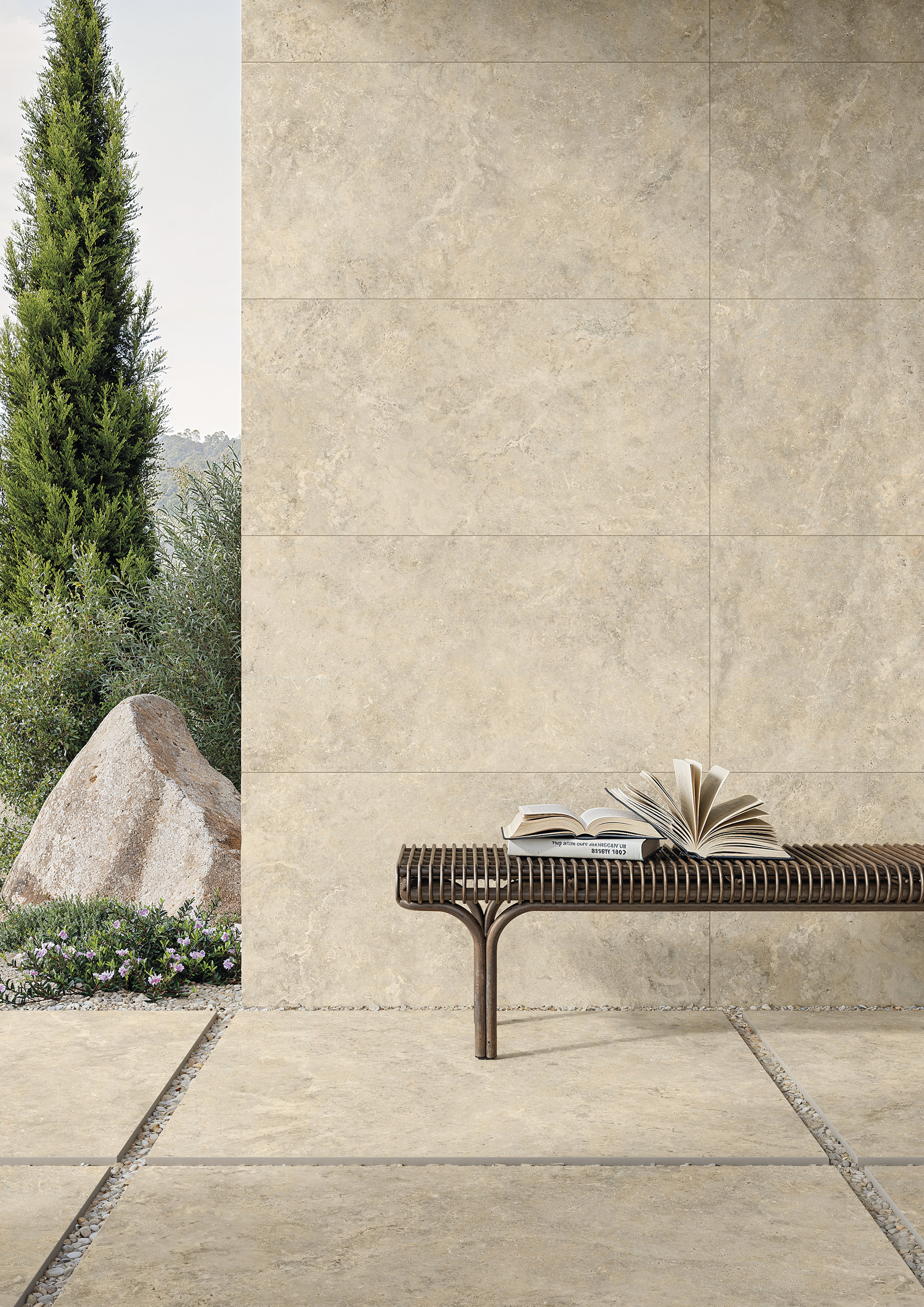 Carrelage extérieur beige aspect pierre naturelle pour mur et sol, avec banc de jardin.