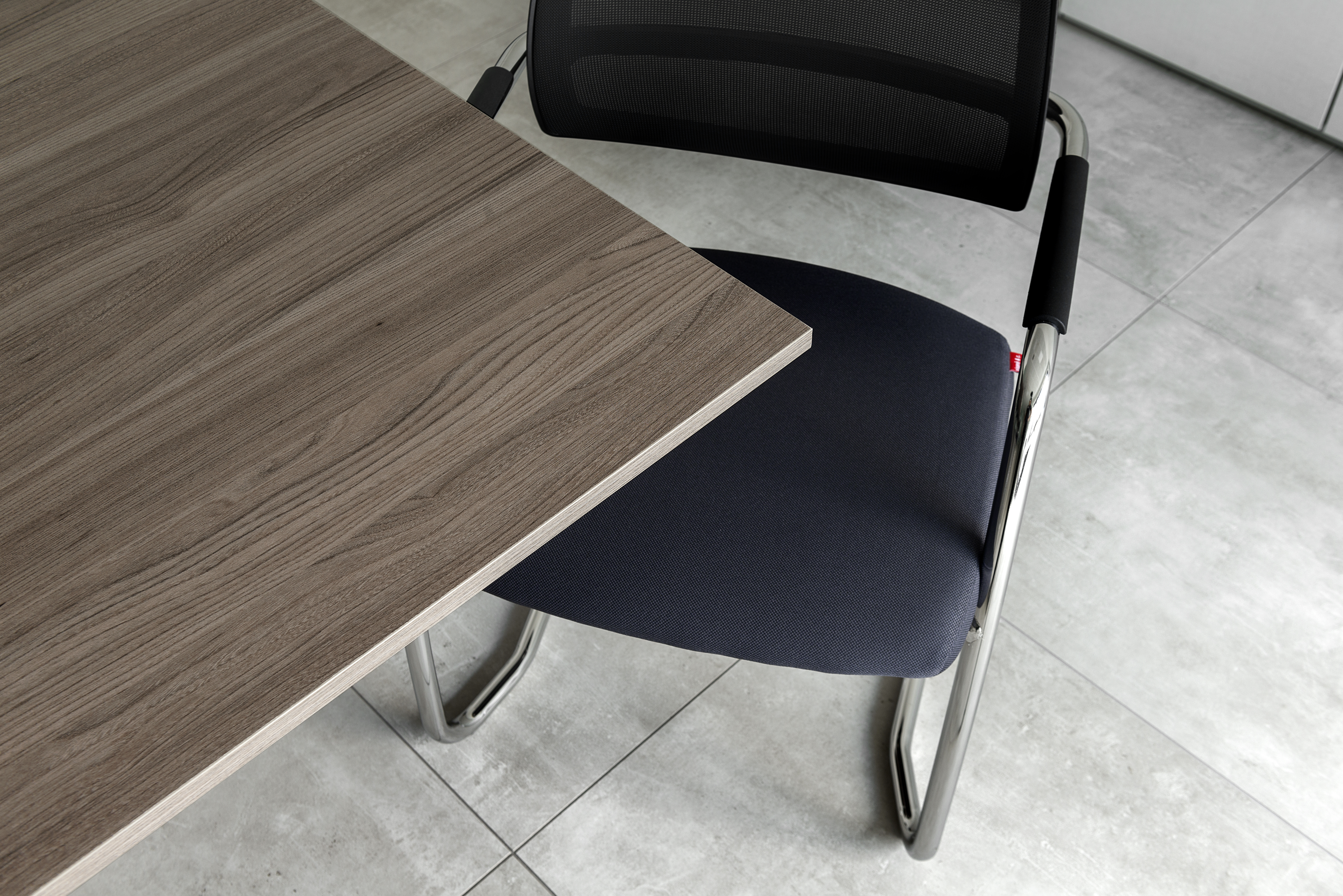Intérieur : carreaux gris clair, table et chaise en bois.